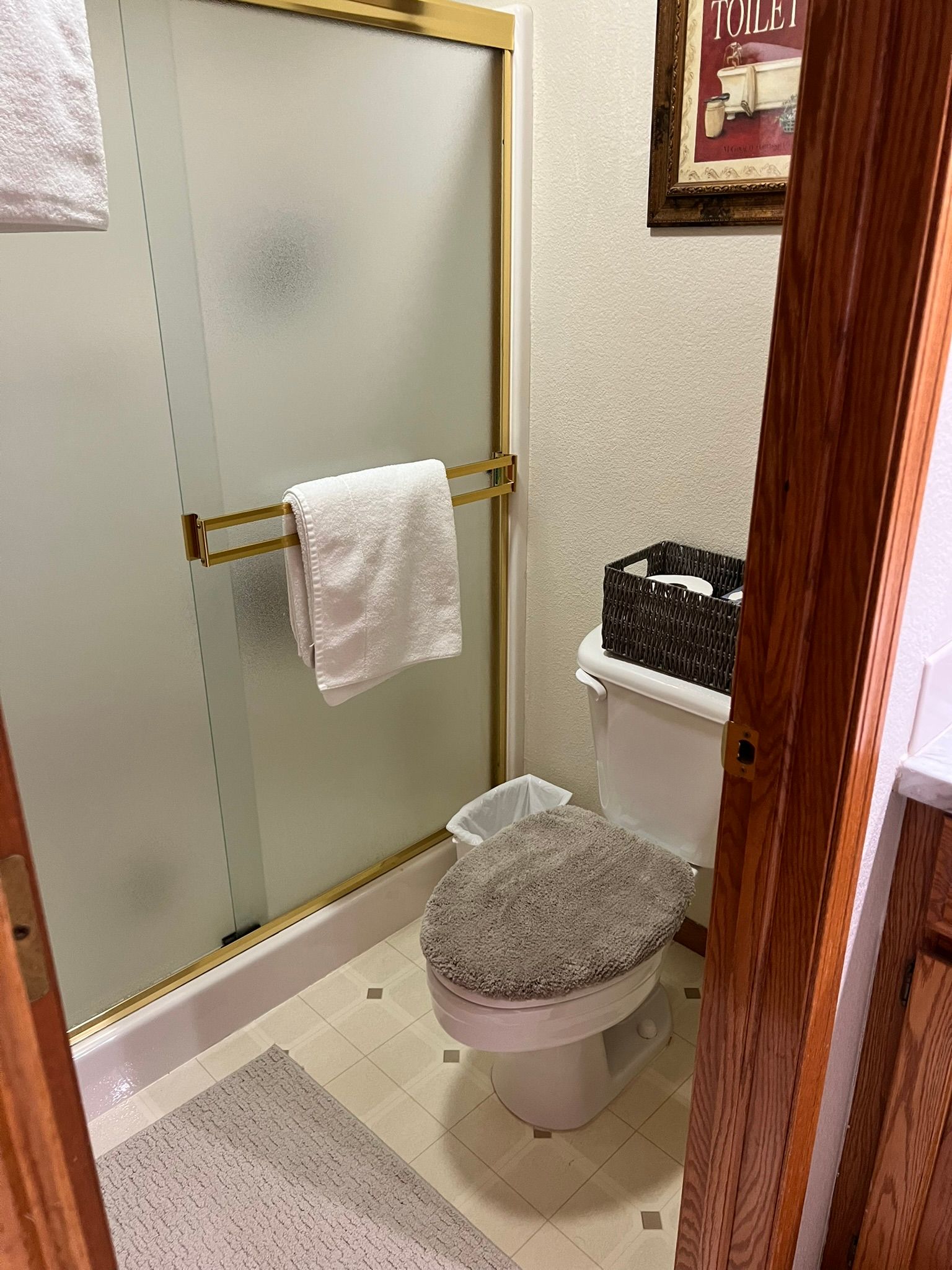 A bathroom with a toilet , shower , and towel rack.