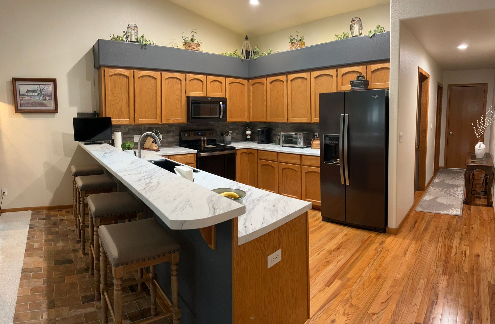 A kitchen with wooden cabinets , stainless steel appliances and a black refrigerator.