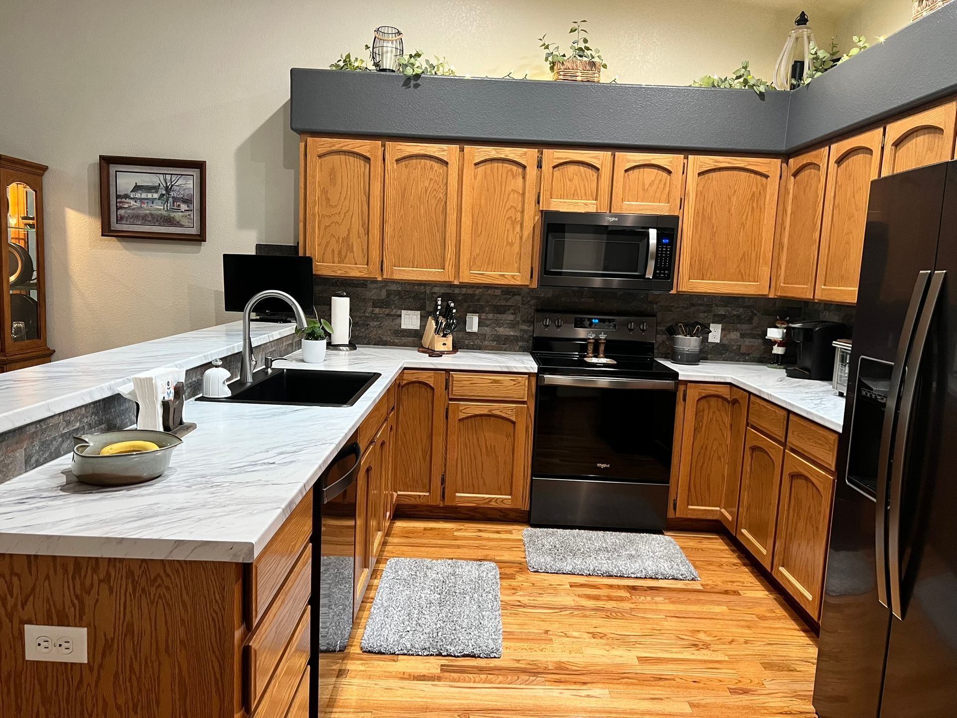 A kitchen with wooden cabinets , stainless steel appliances , a sink , and a refrigerator.