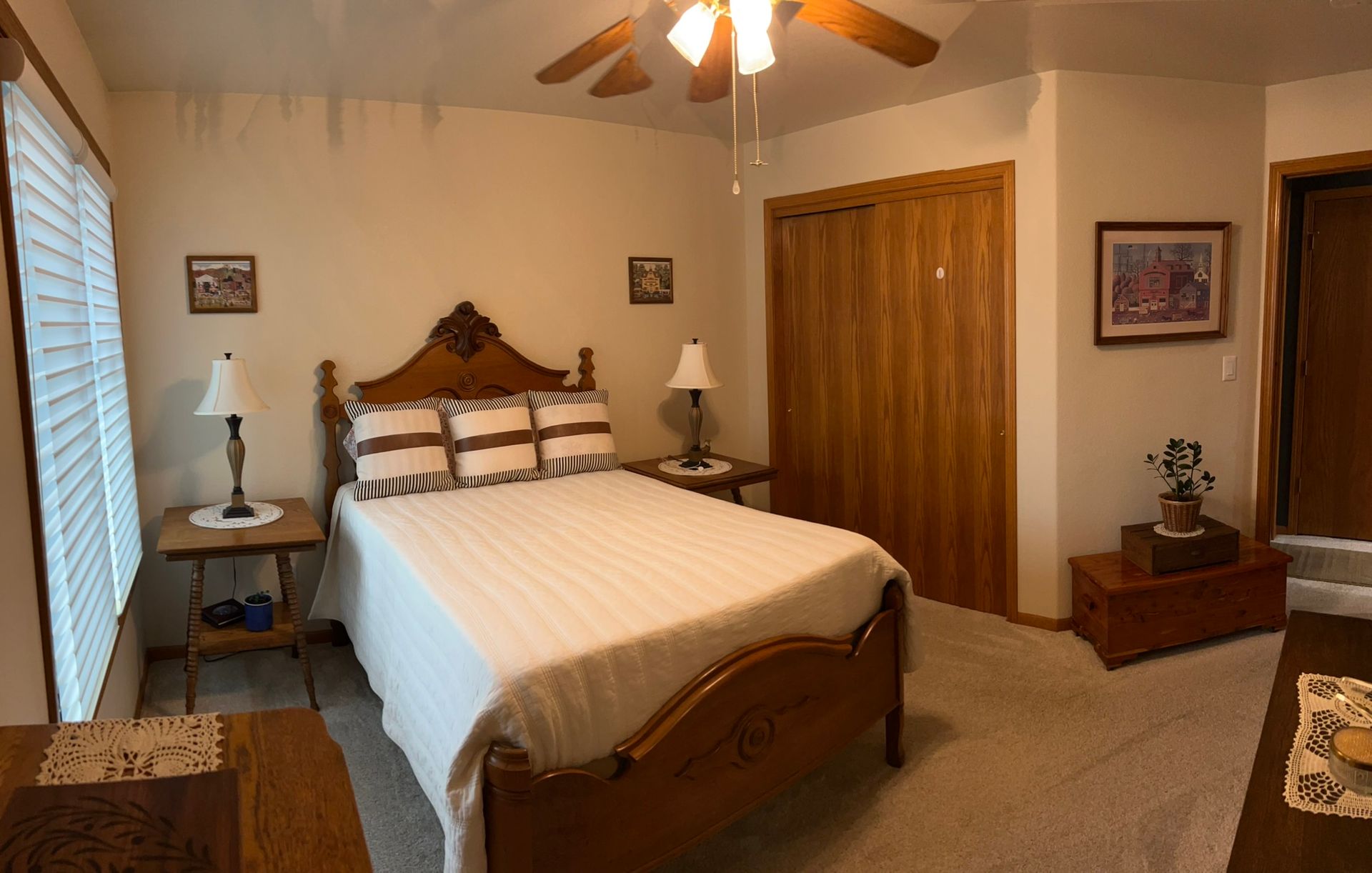 A bedroom with a bed , nightstand , lamp and ceiling fan.
