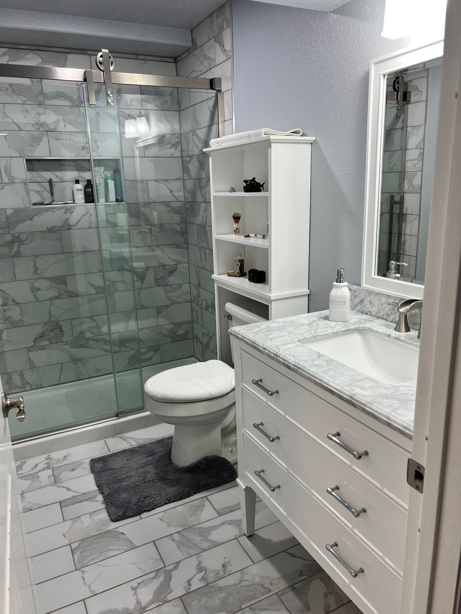 A bathroom with a toilet , sink , mirror and shower.