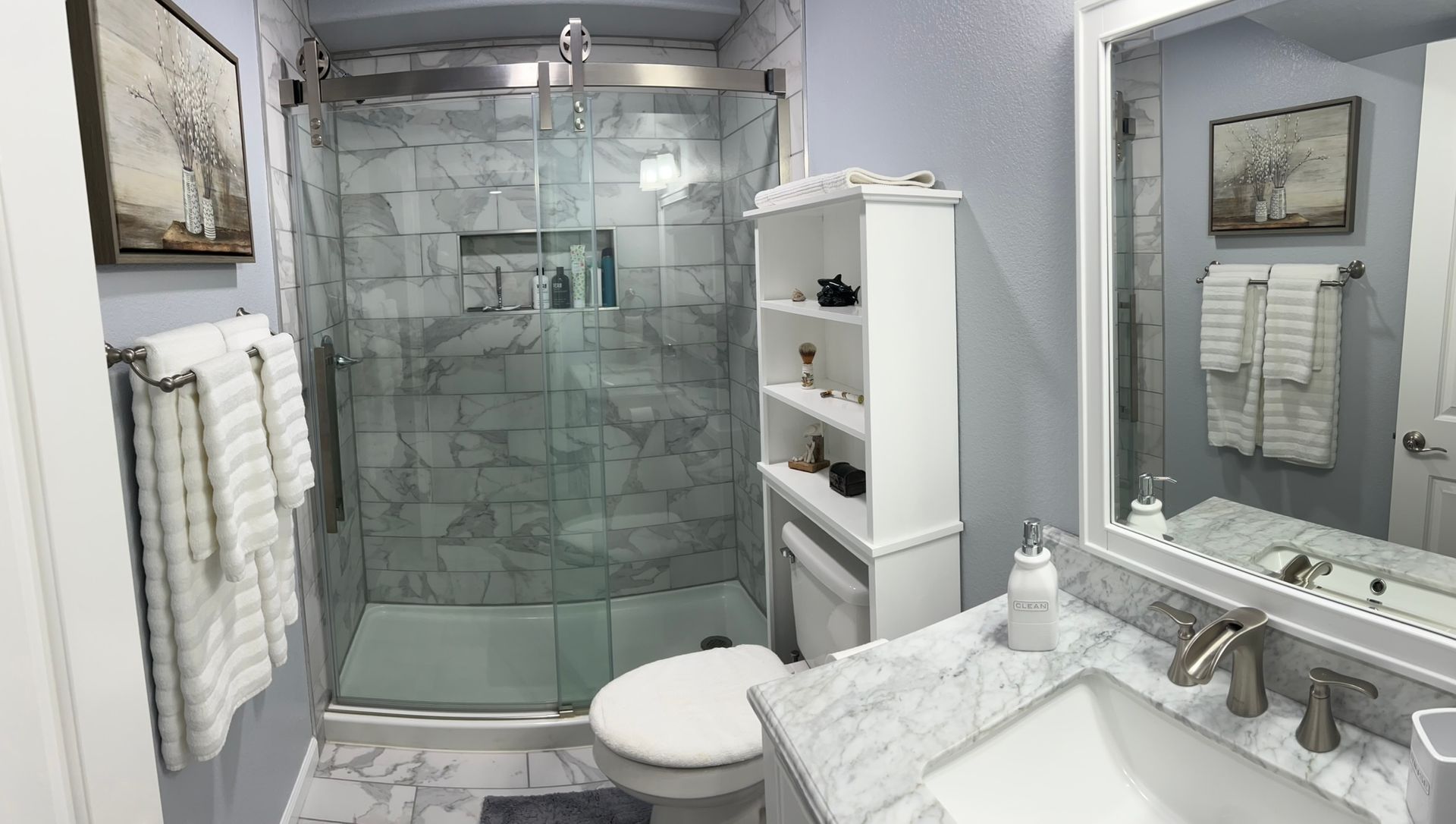 A bathroom with a toilet , sink , mirror and walk in shower.