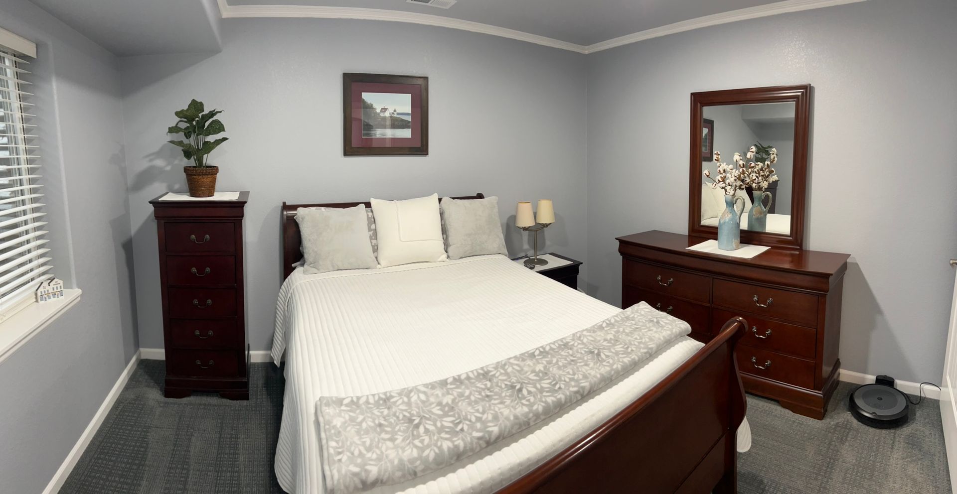 A bedroom with a bed , dresser and mirror