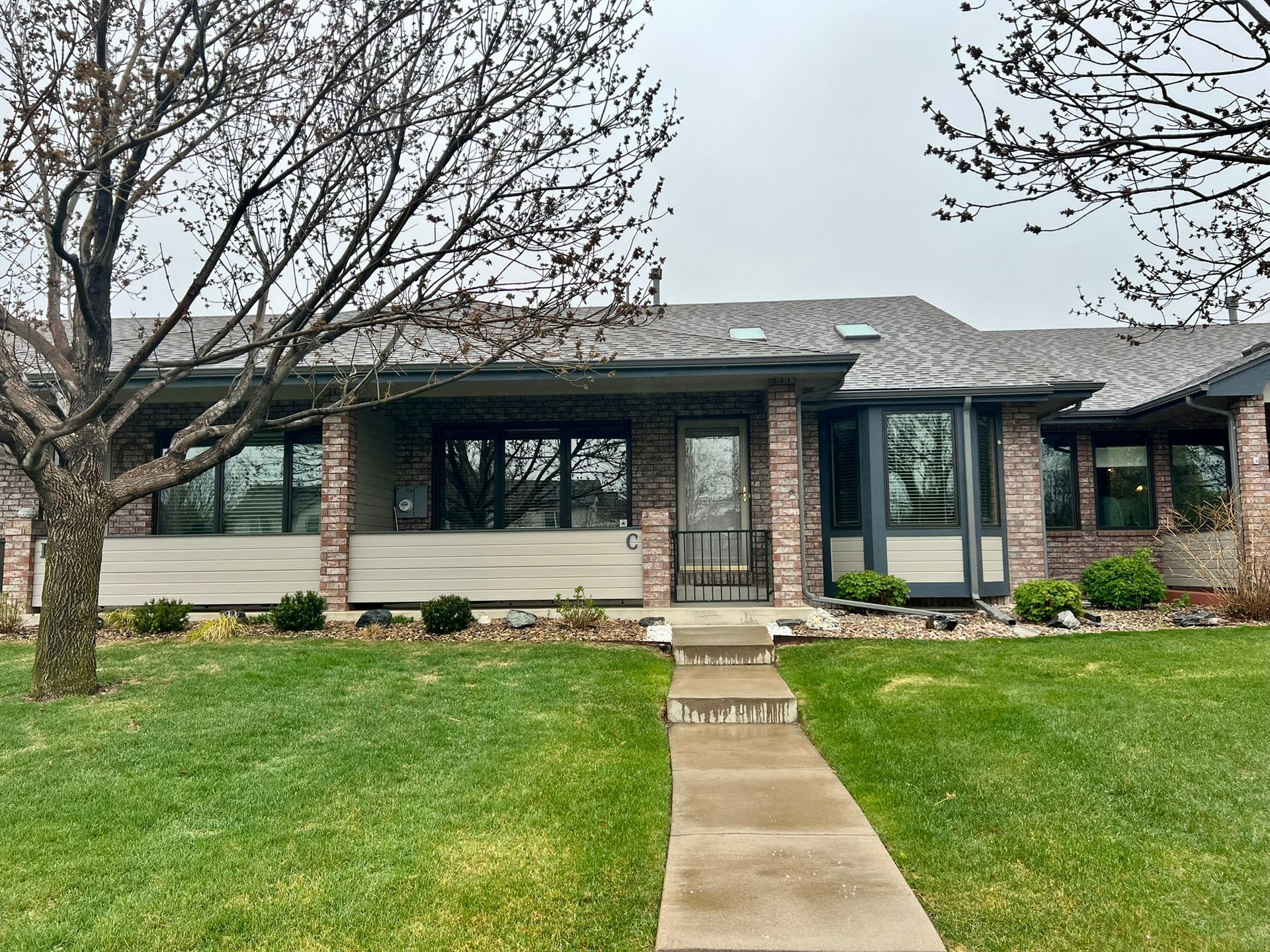 A brick house with a gray roof and a walkway leading to it.