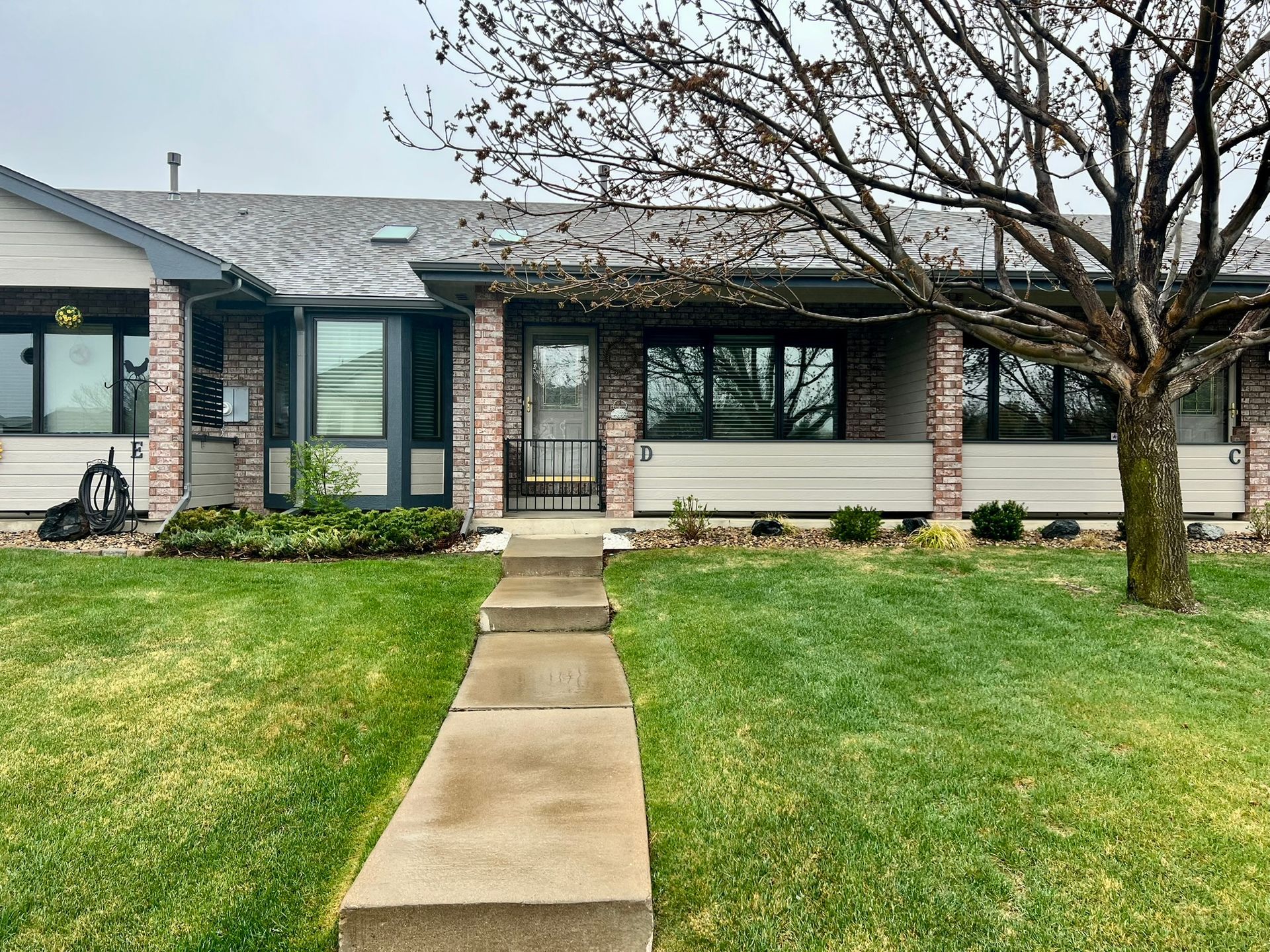 A house with a lush green lawn and a tree in front of it.