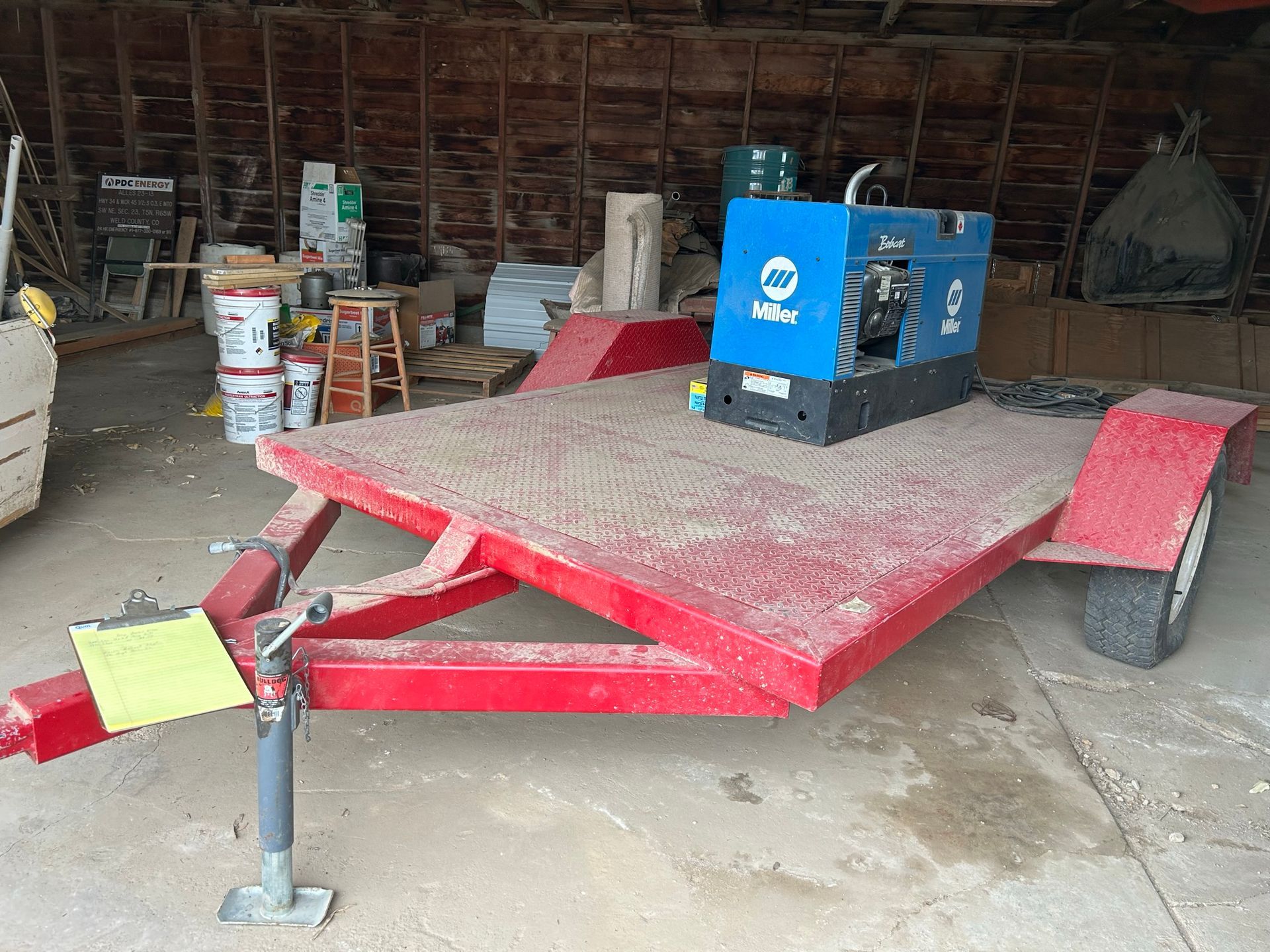 A welding machine is sitting on top of a red trailer.
