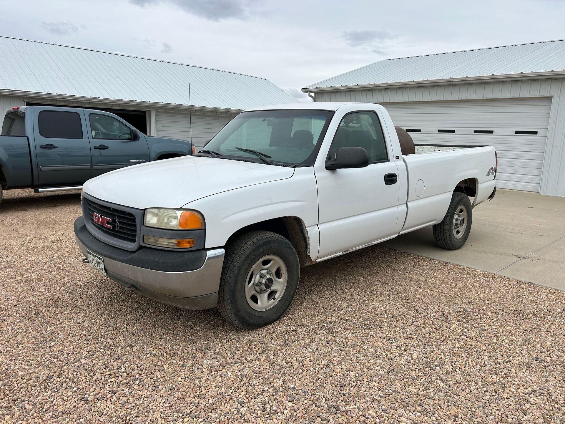 A white gmc truck is parked in front of a garage.