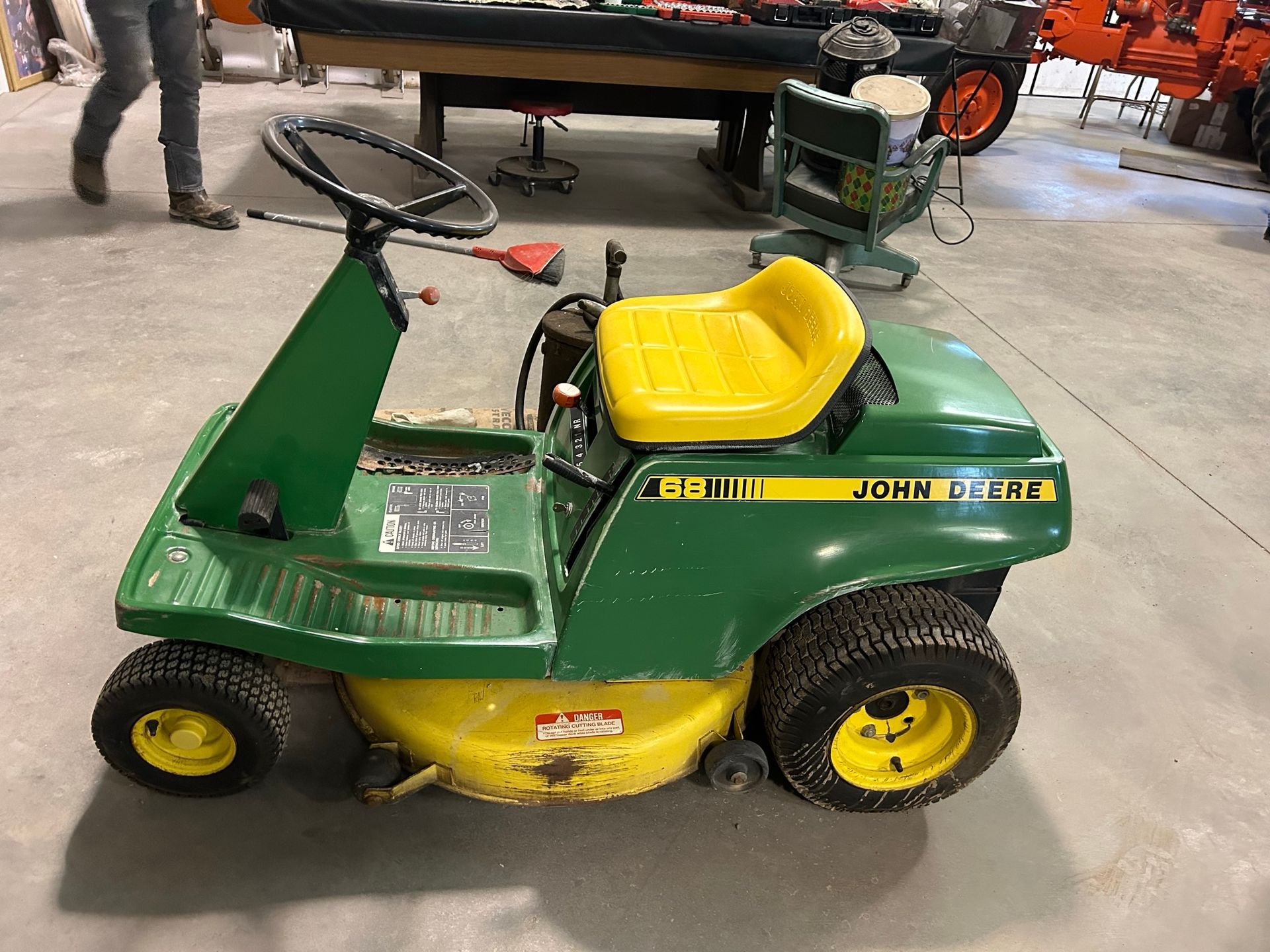 A green and yellow john deere lawn mower is parked in a garage.