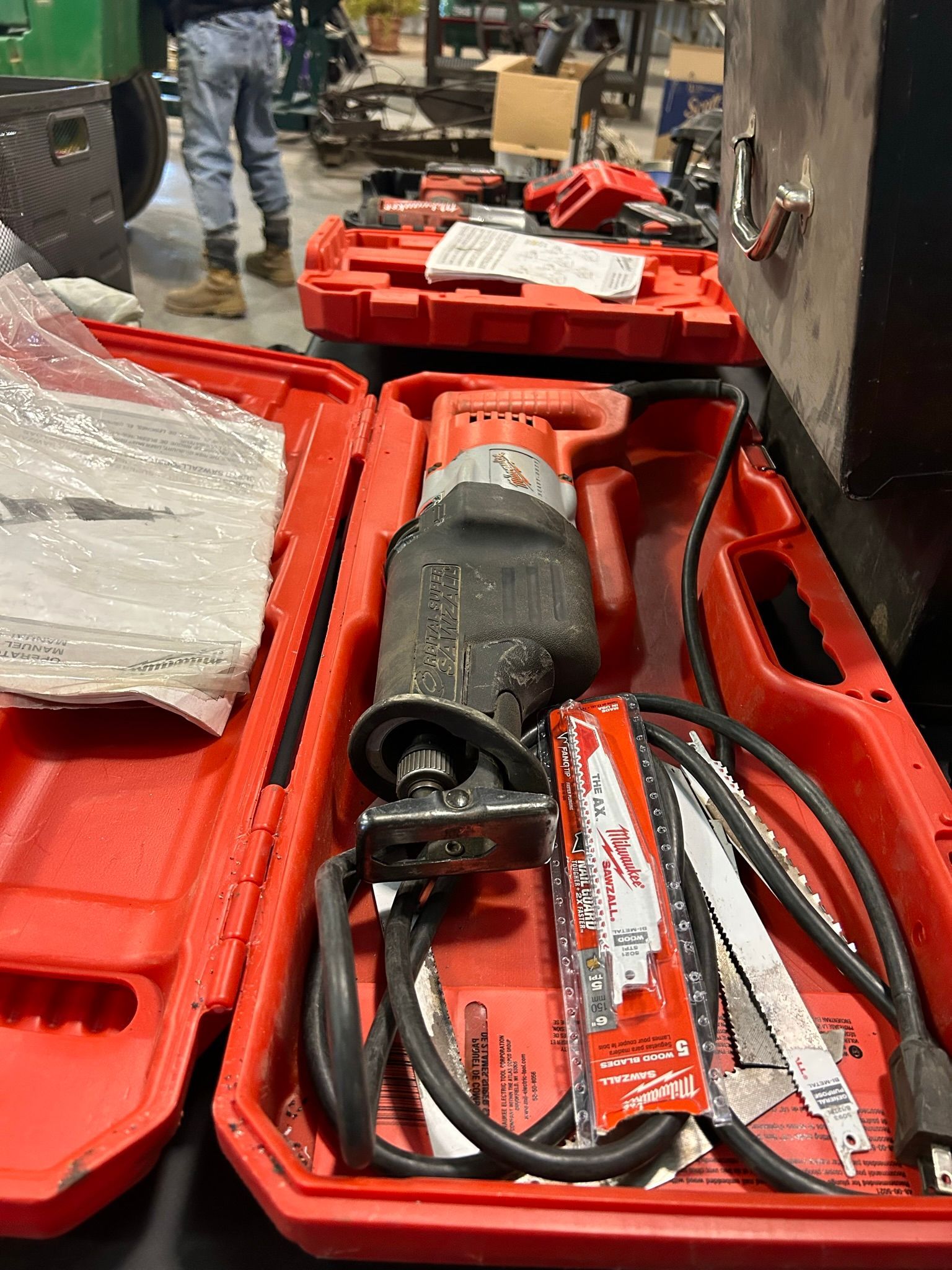 A saw is sitting in a red case on a table.