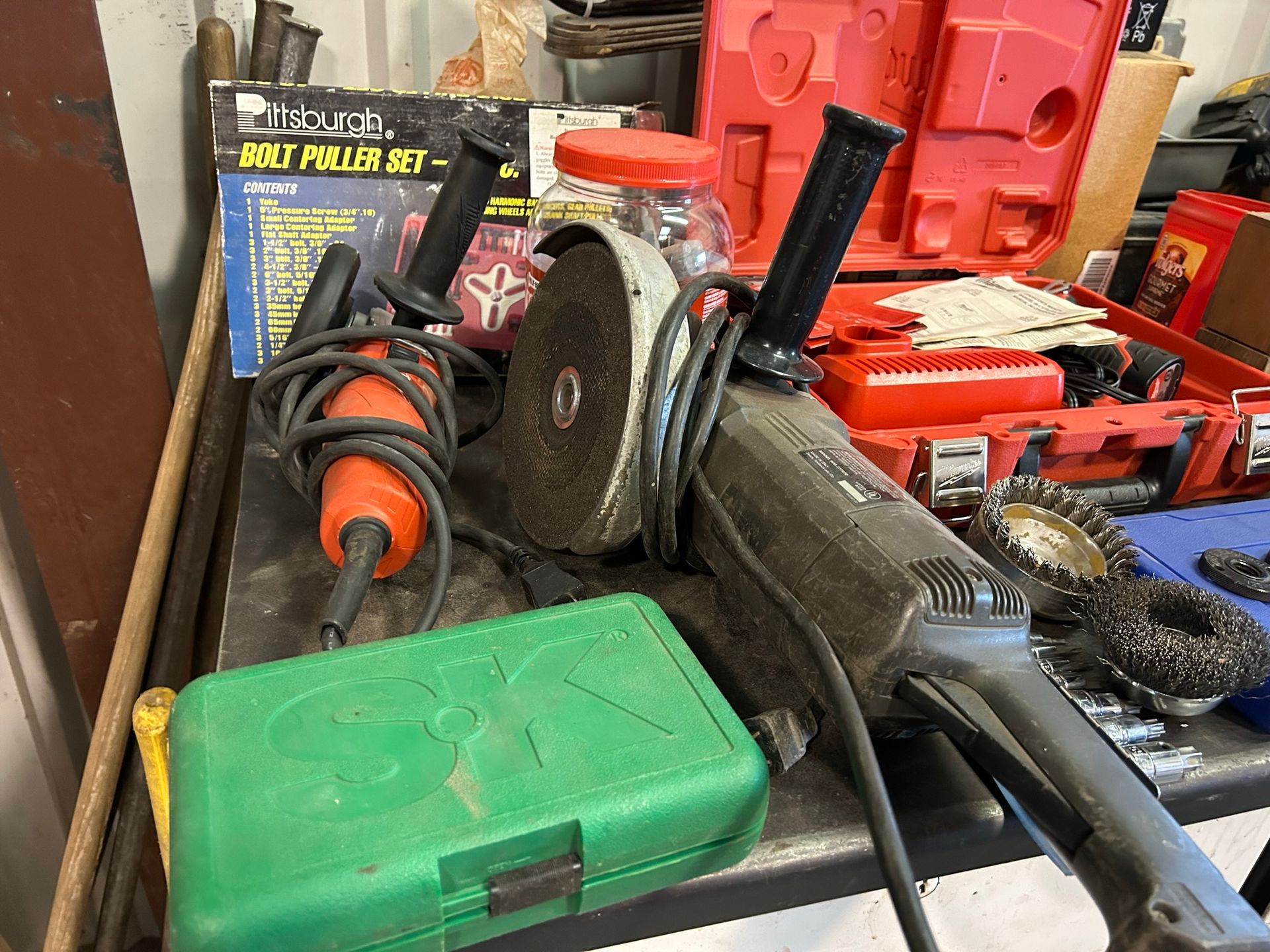 A bunch of tools are on a table including a grinder