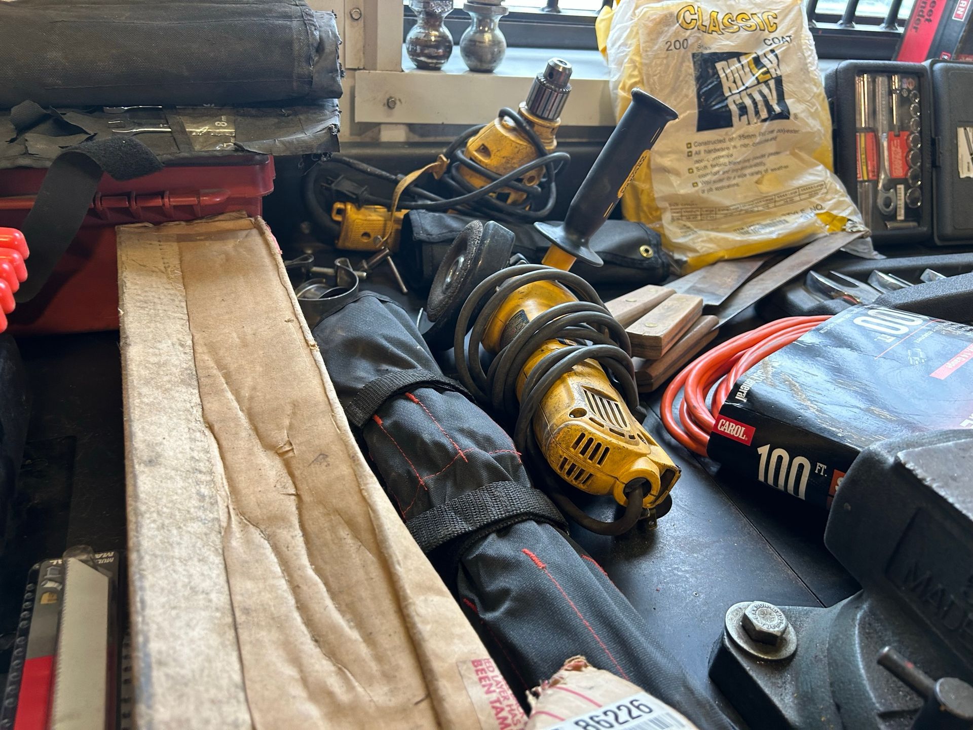 A bunch of tools are laying on a table including a dewalt tool