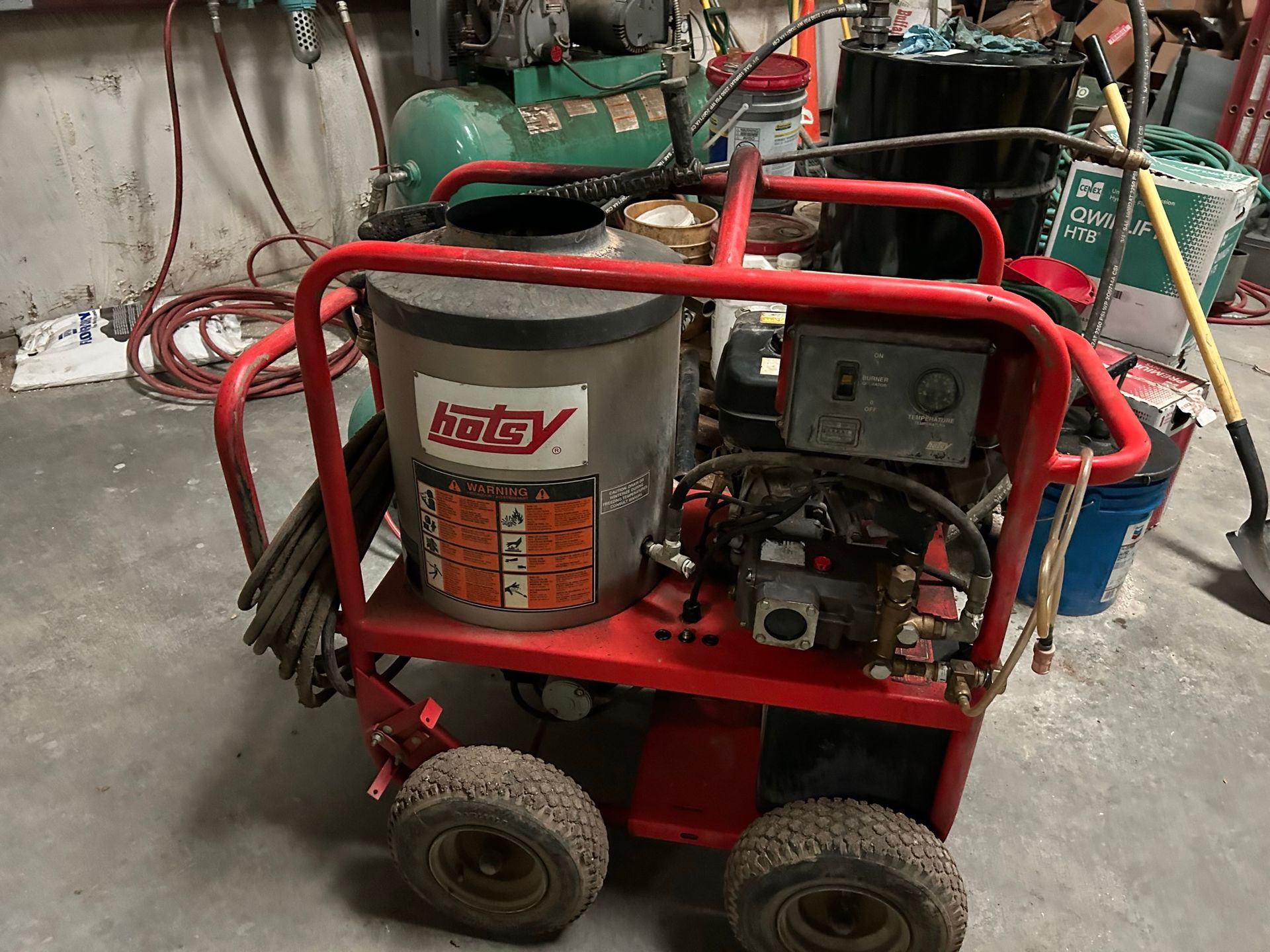 A red and silver machine with wheels is sitting in a garage.