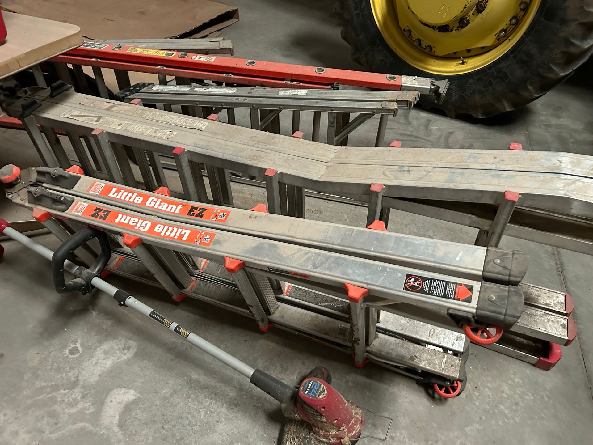 A ladder is sitting on the ground next to a tractor.