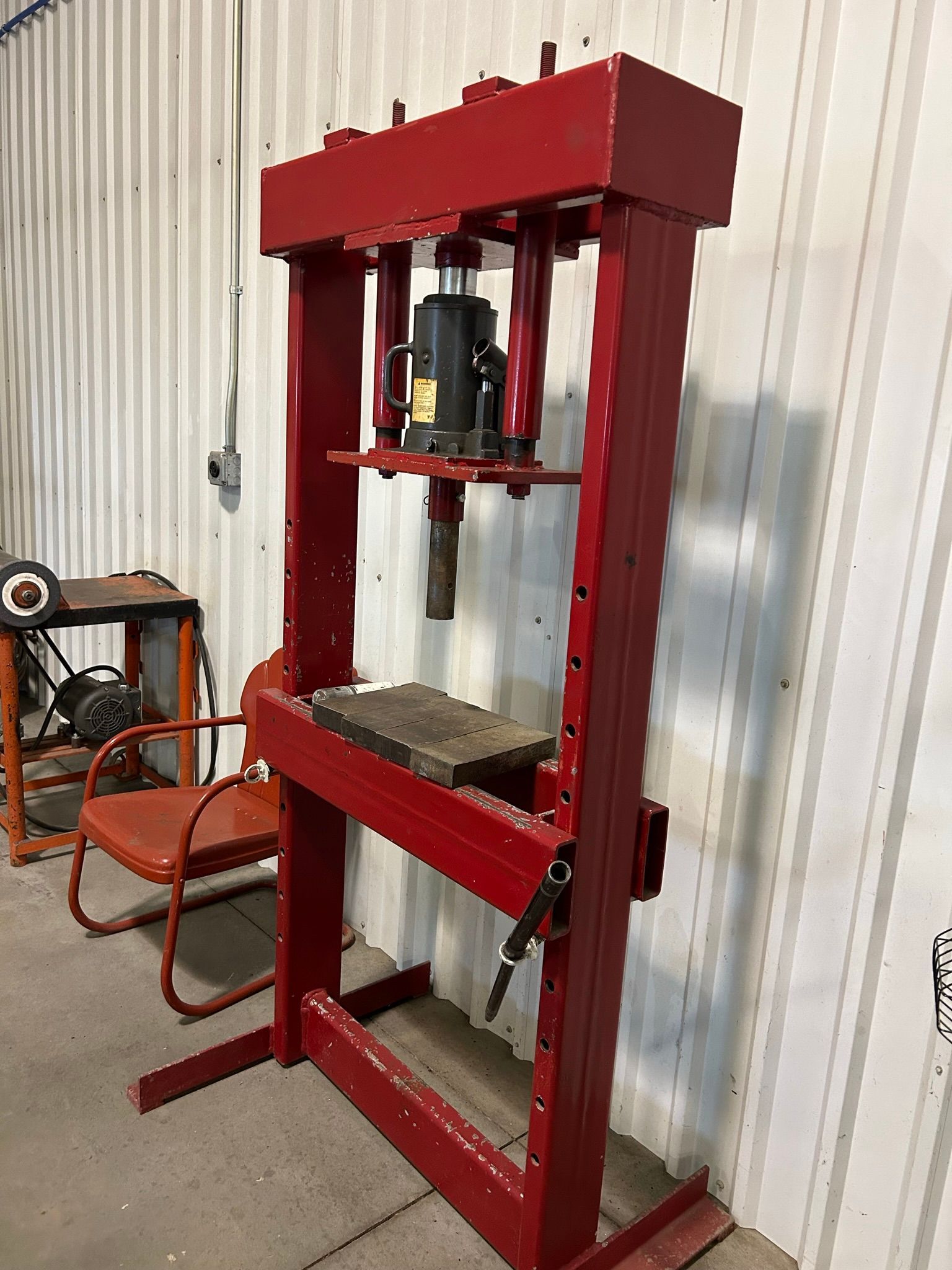 A red machine is sitting in a room next to a chair.