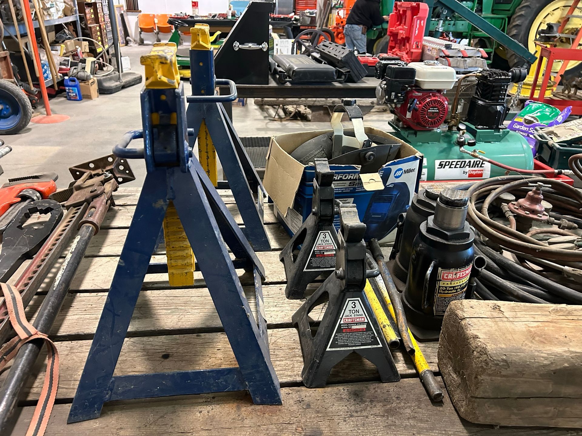 A bunch of tools are sitting on a wooden table in a garage.