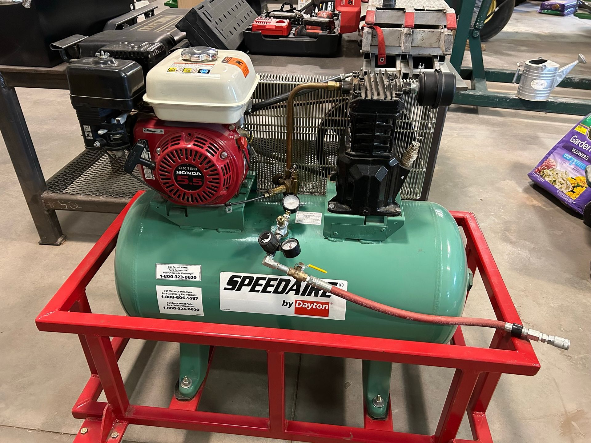 A green air compressor is sitting on top of a red frame.