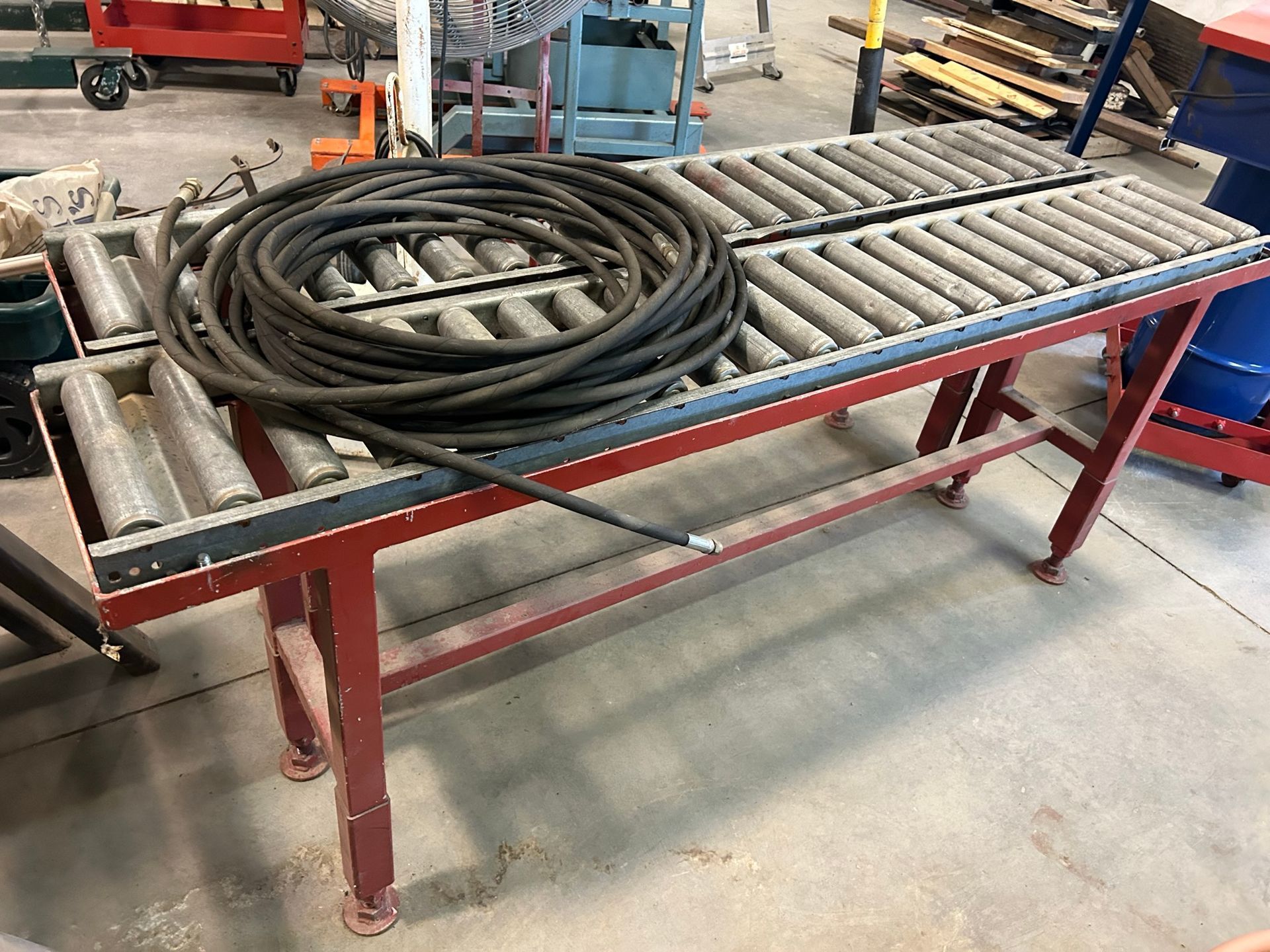 A conveyor belt with a hose on top of it in a warehouse.