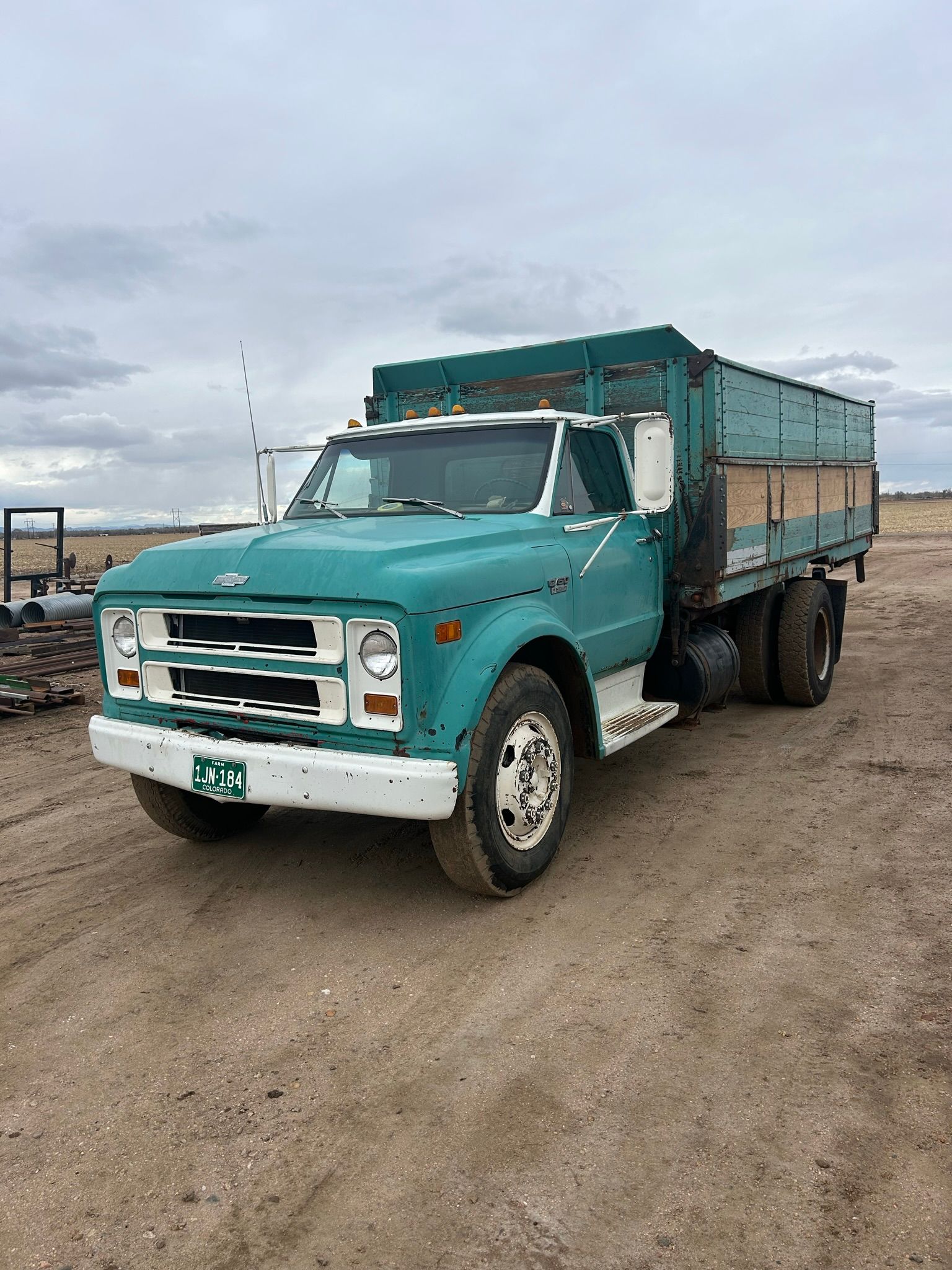 A blue truck is parked in a dirt field.