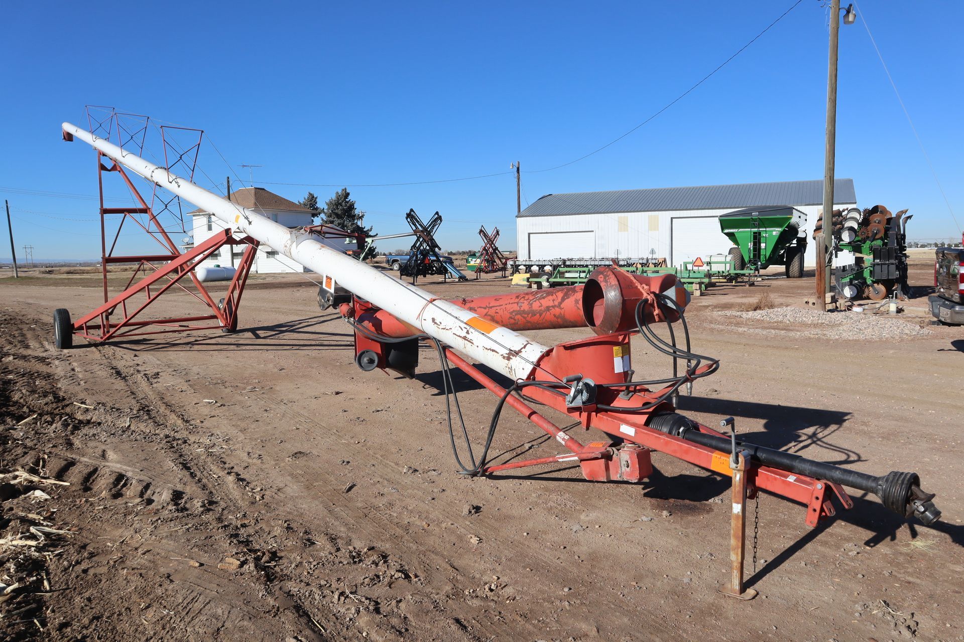 A red and white machine is sitting in a dirt field.