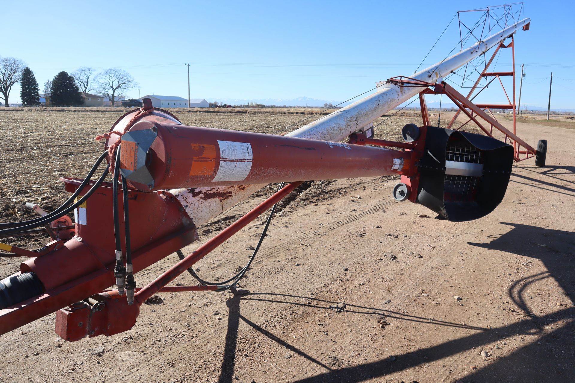 A red and white machine is sitting on top of a dirt field.