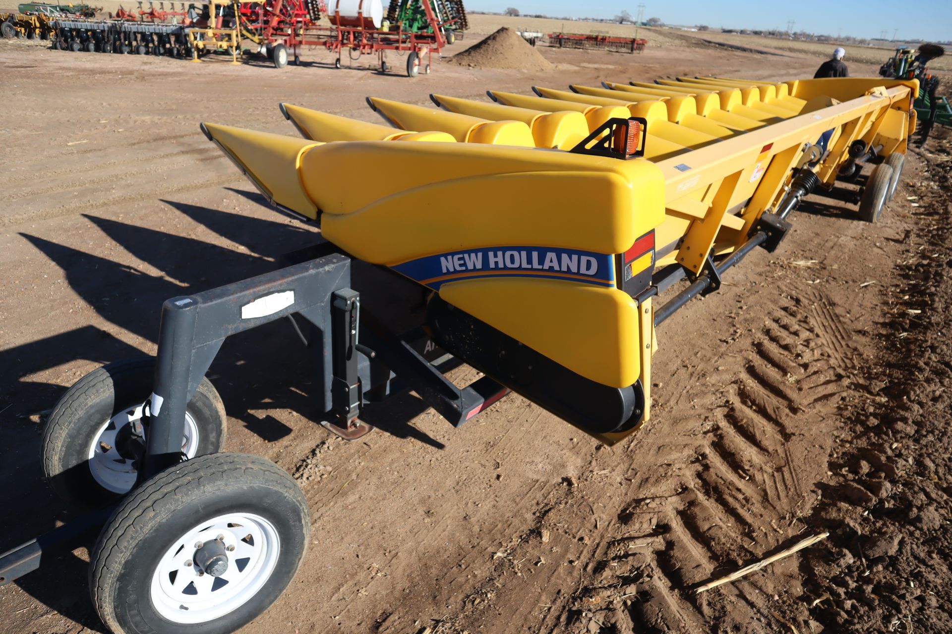 A new holland corn planter sits in a dirt field