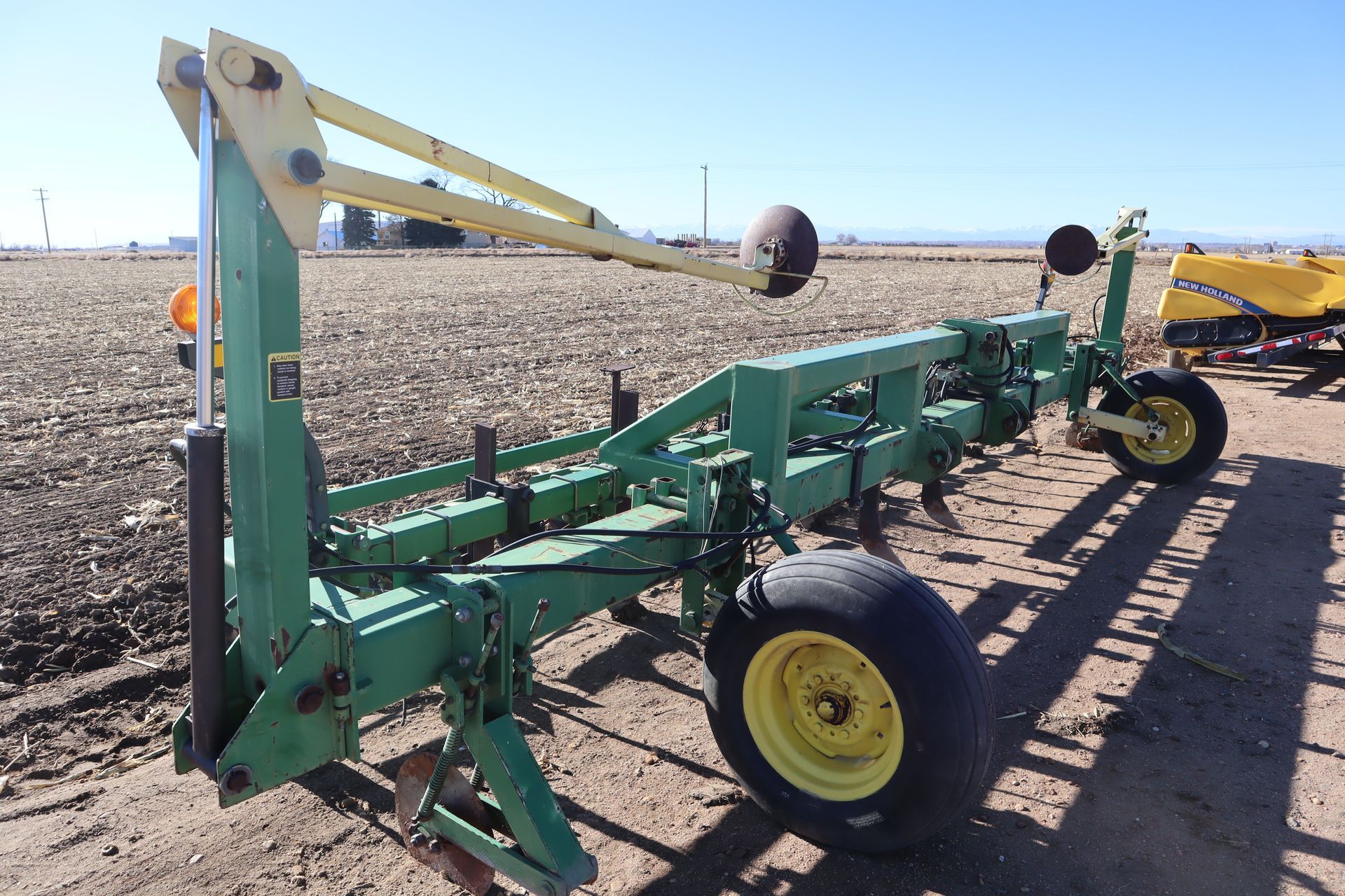 A green and yellow tractor is parked in a dirt field.