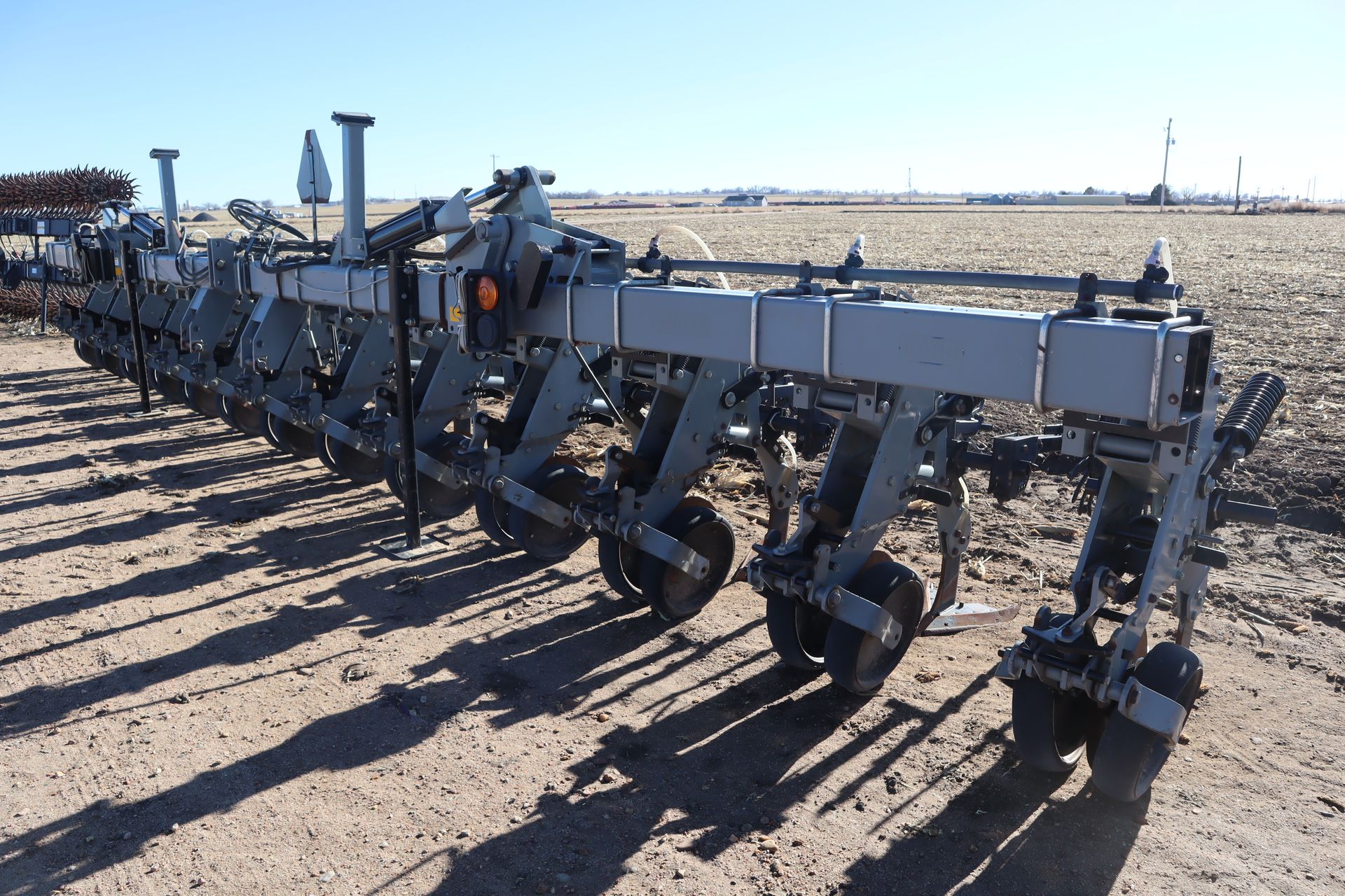 A row of tractors are parked in a dirt field.