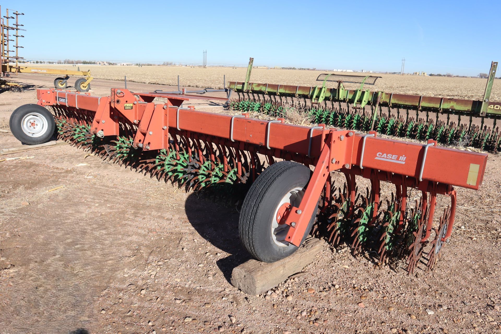 A red and green tractor is parked in a dirt field