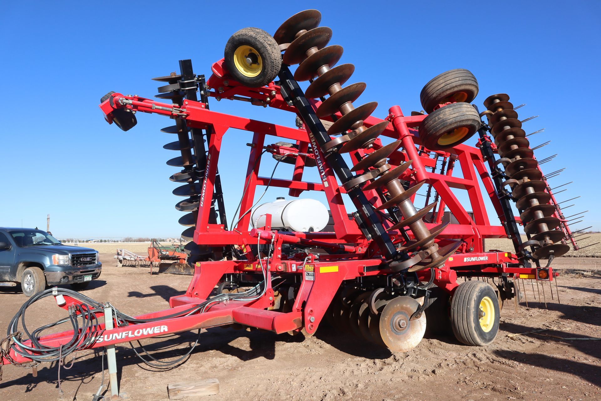 A red and black tractor is parked in a dirt field