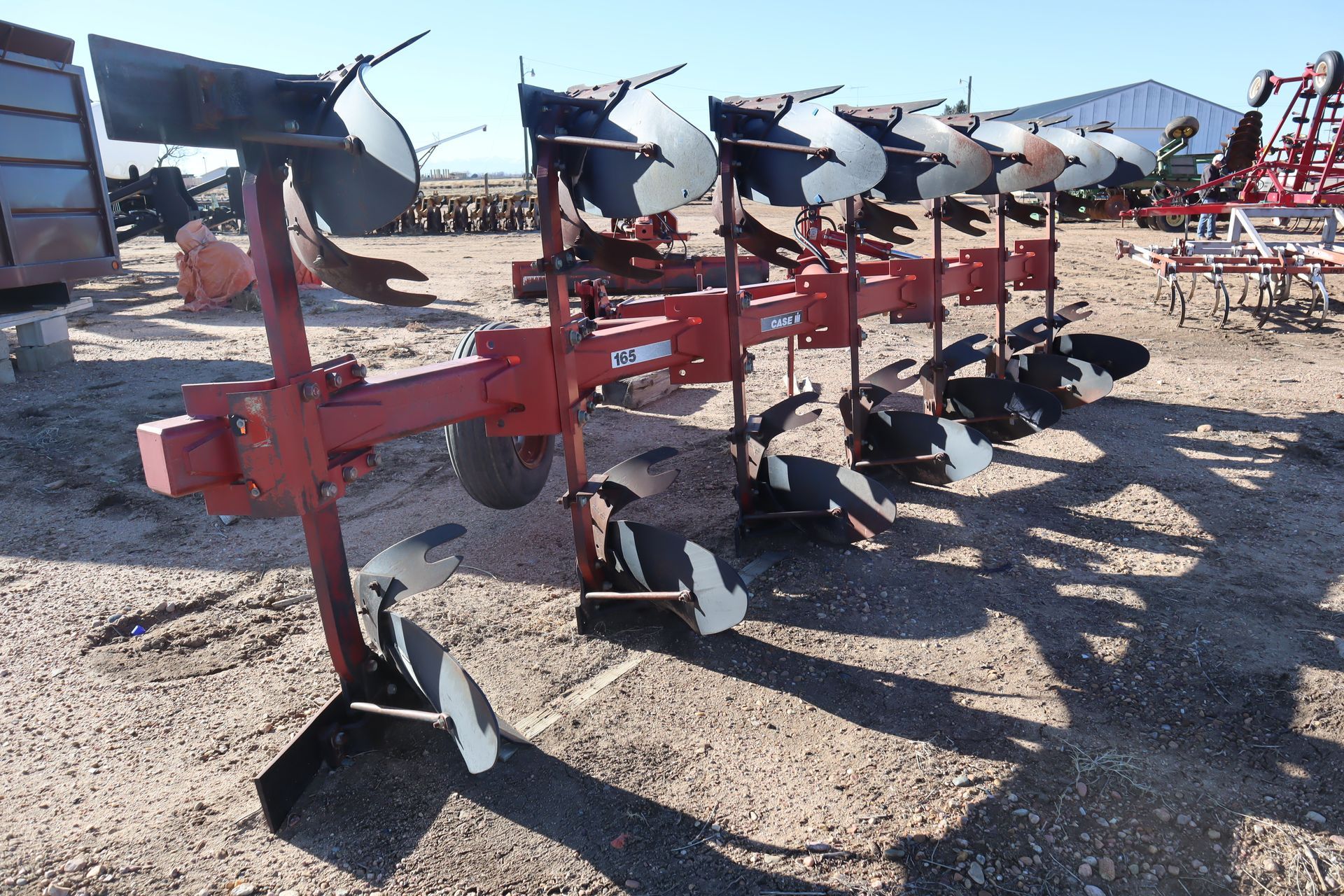 A red plow is sitting in the dirt in a field