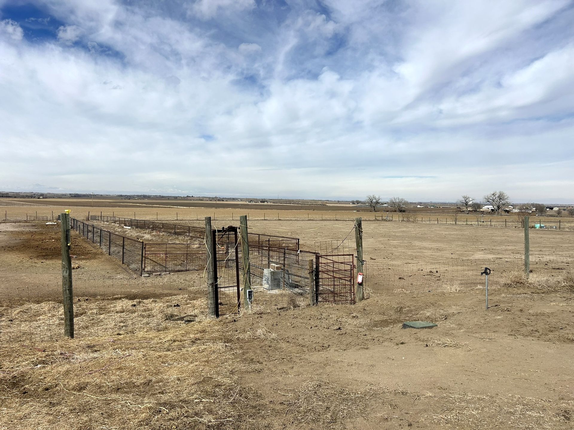 A dirt field with a barbed wire fence in the foreground