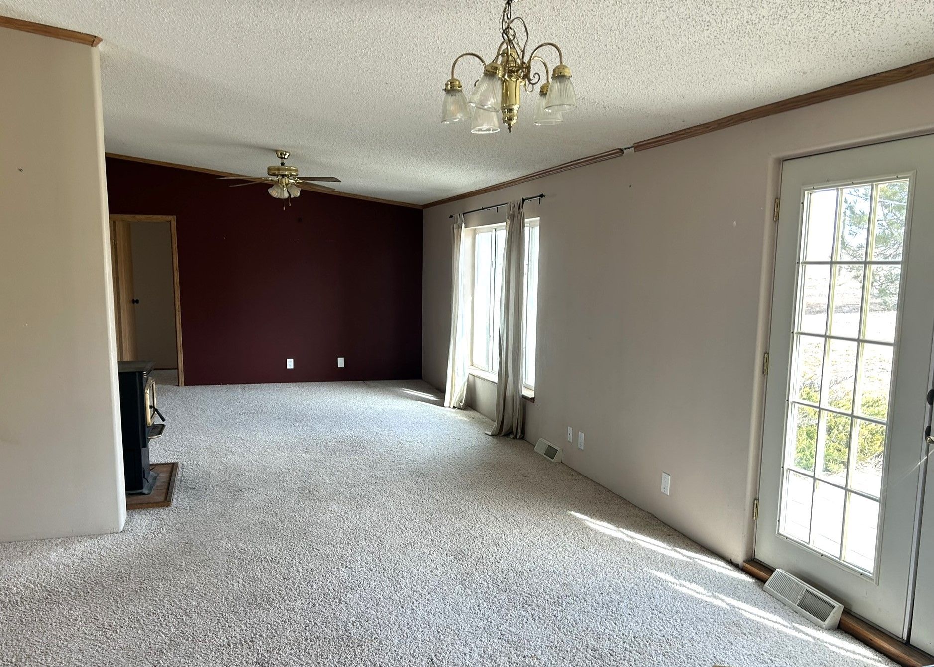 An empty living room with a ceiling fan and a door.
