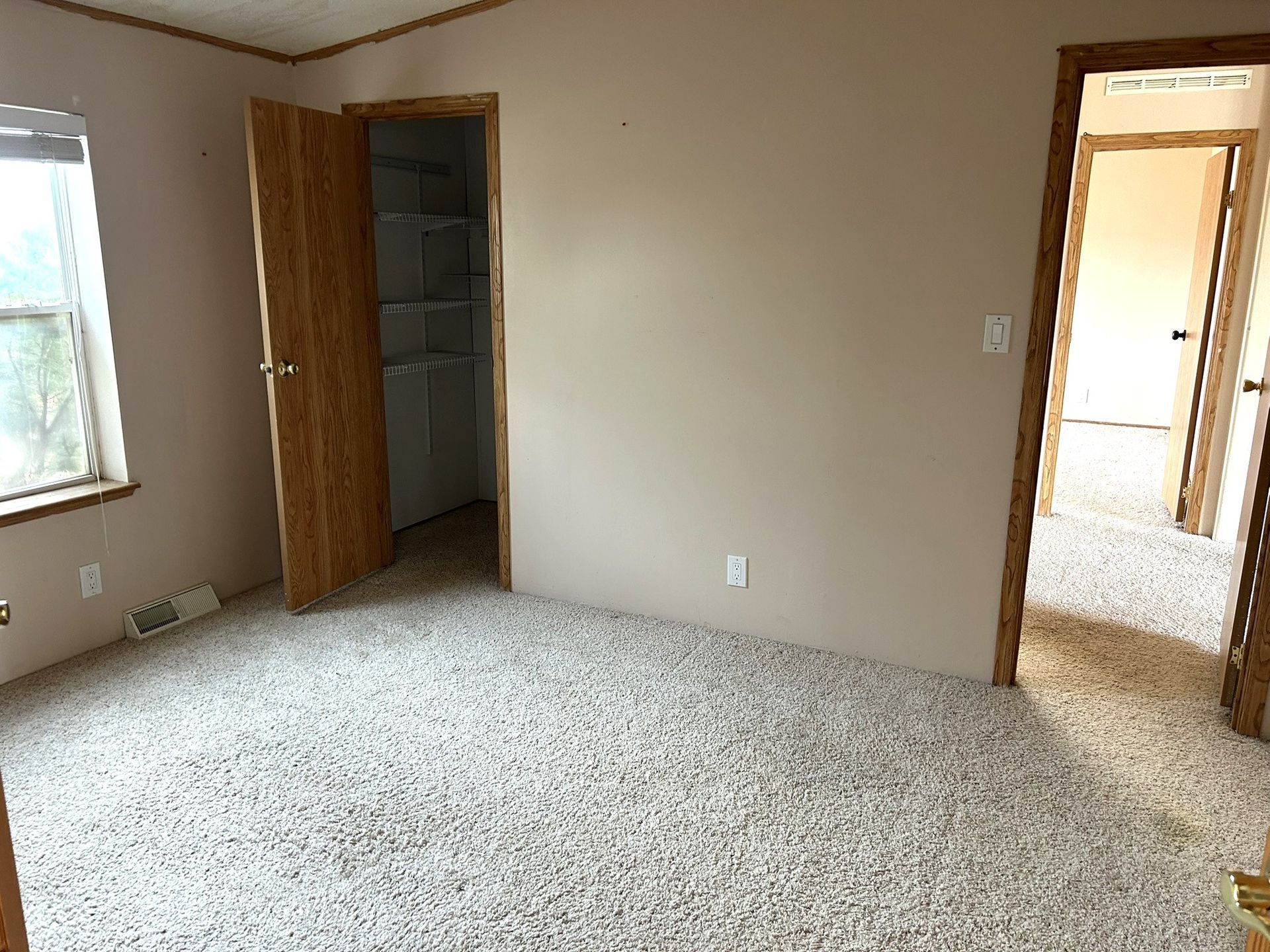 An empty room with a carpeted floor and a window.