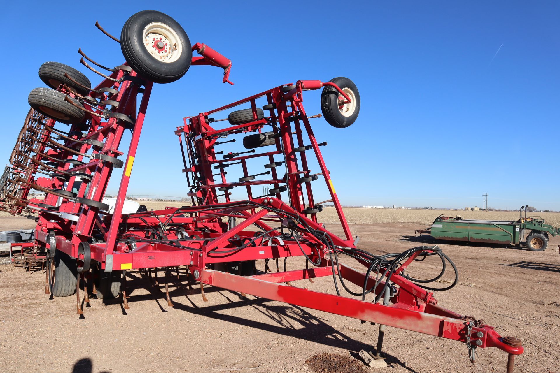 A red tractor is sitting on top of a dirt field.
