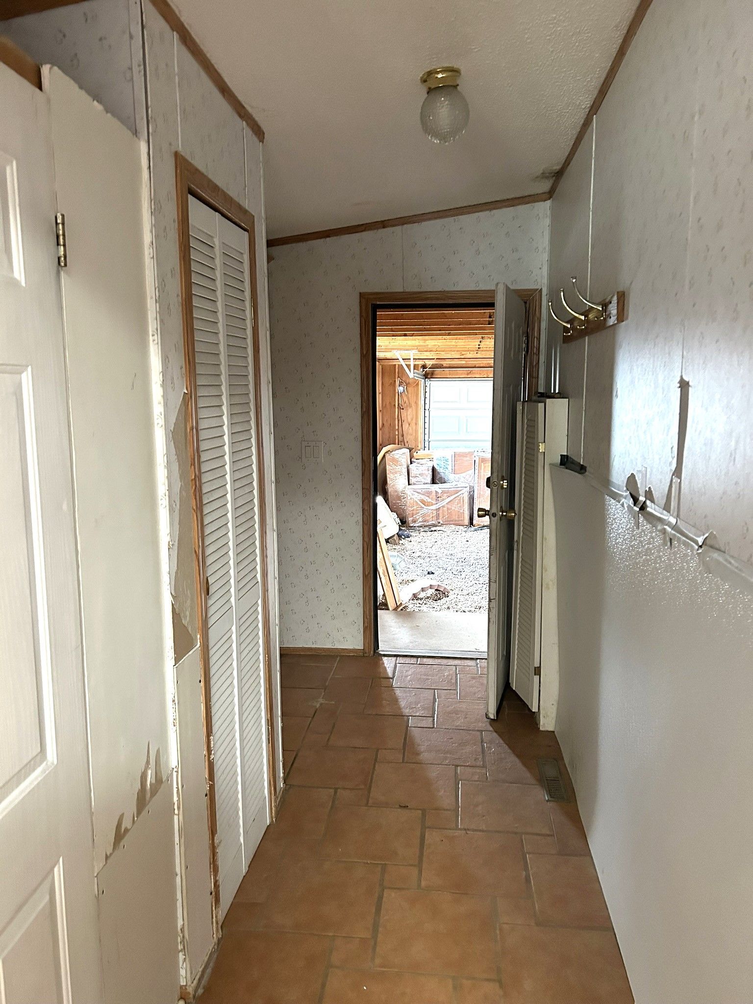 A hallway in a house with a door that is open and a light on the ceiling.