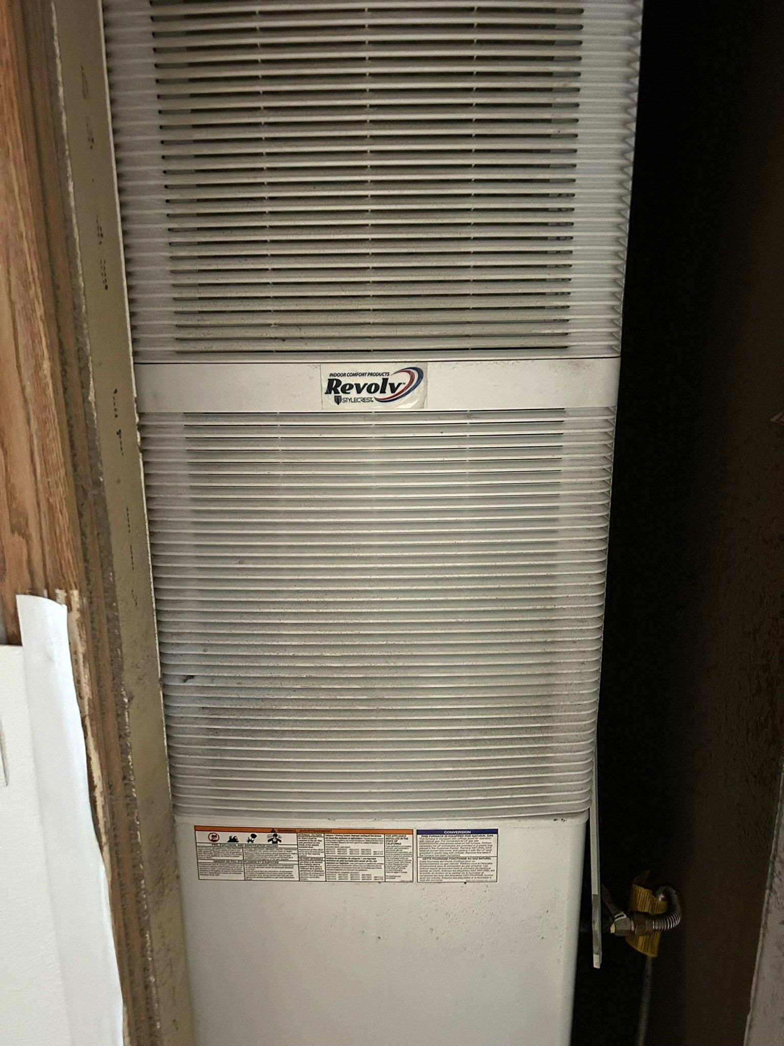 A white air conditioner is sitting in a corner of a room.