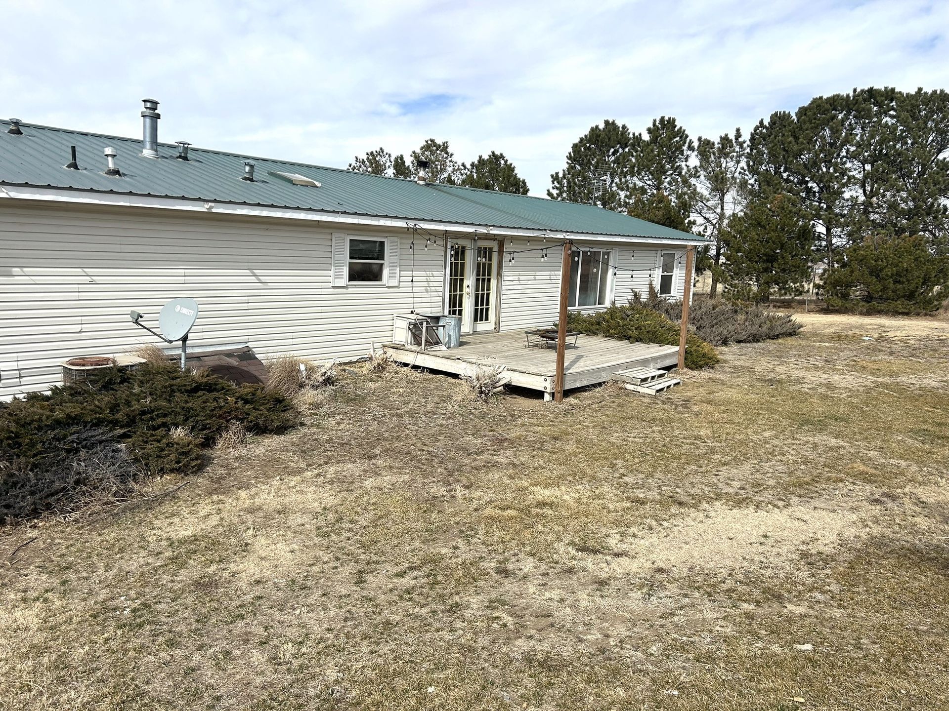 A white house with a green roof is sitting in the middle of a field.