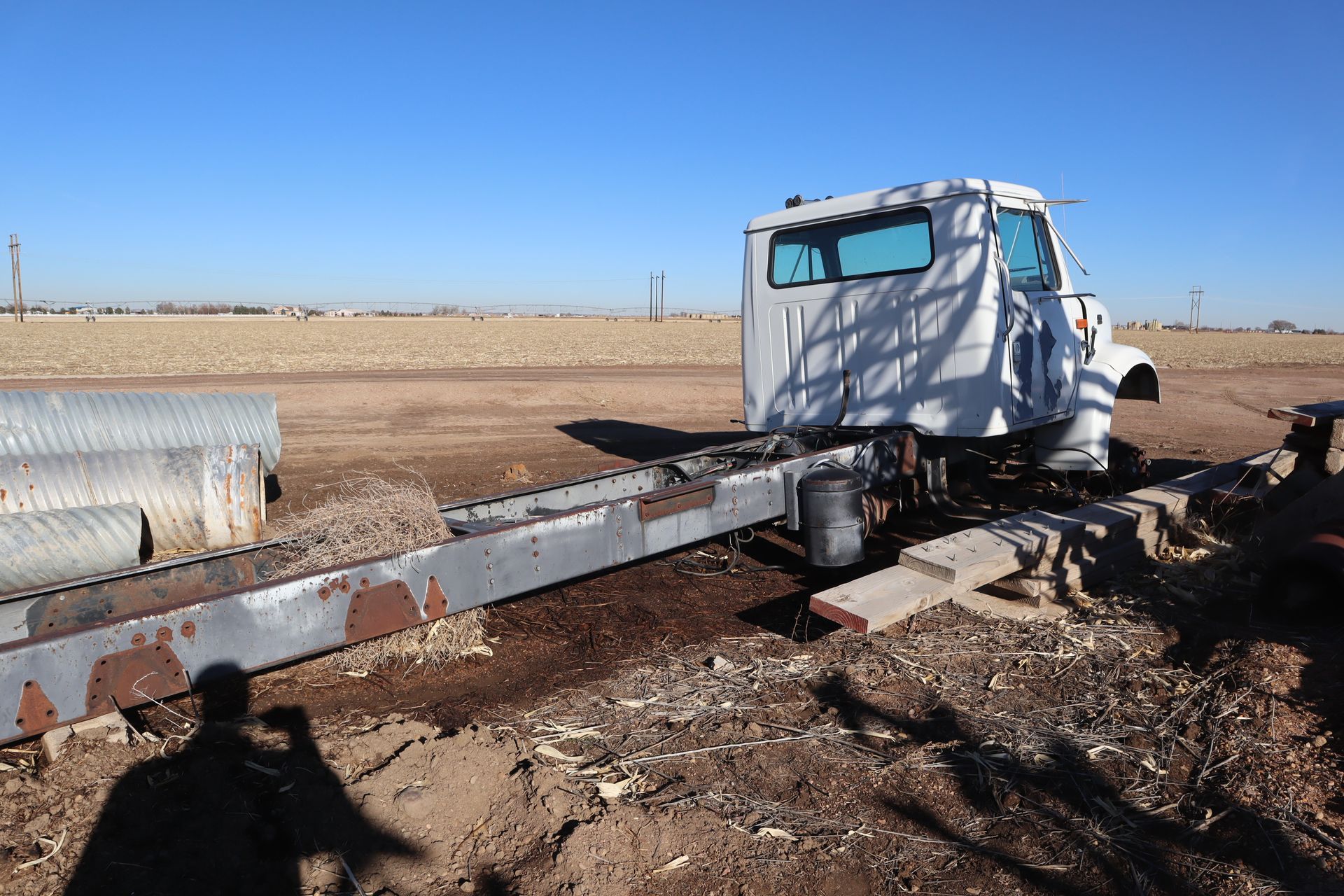 A white truck is sitting in the middle of a dirt field.