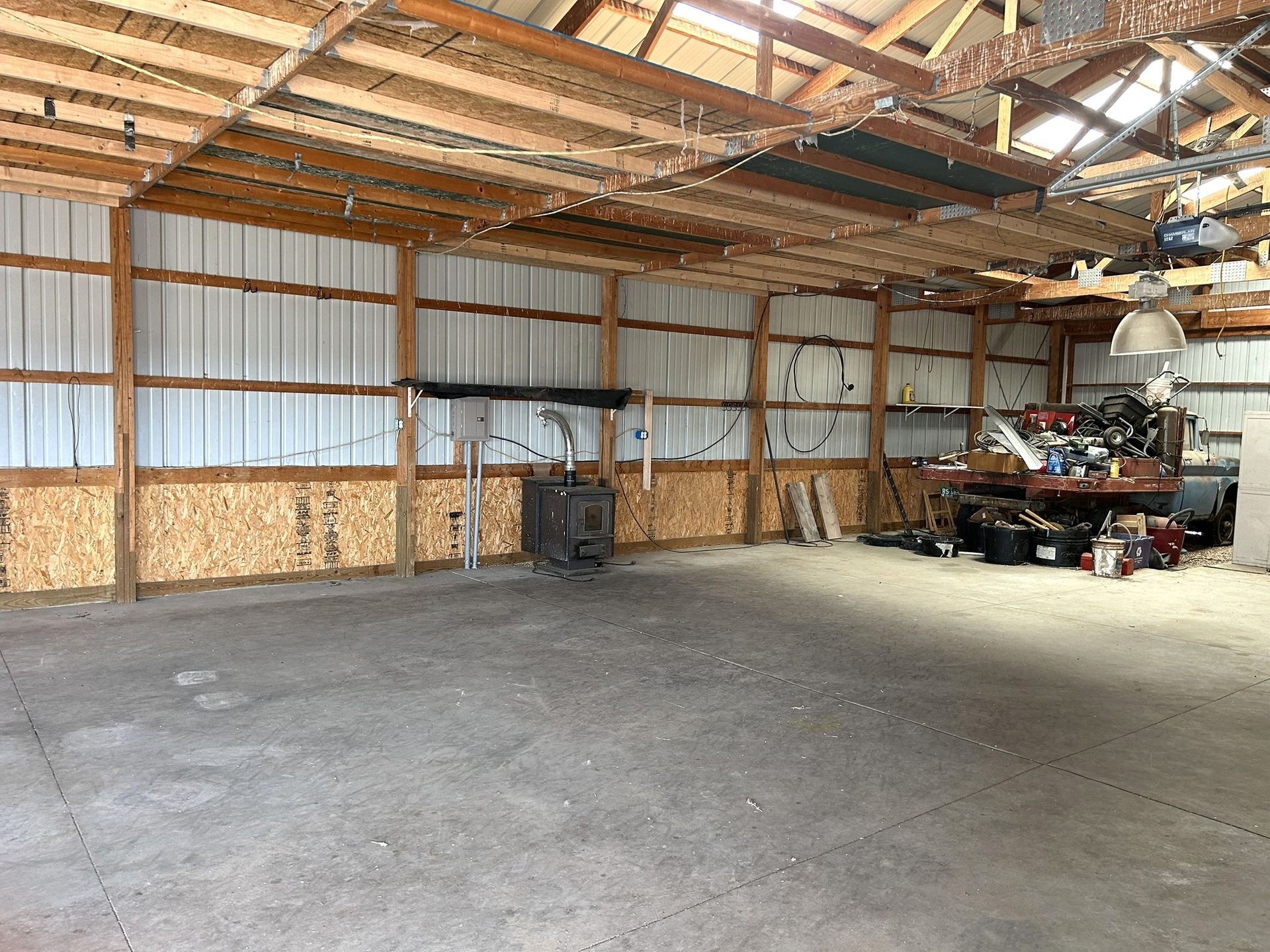 A large empty garage with wooden beams and a concrete floor.