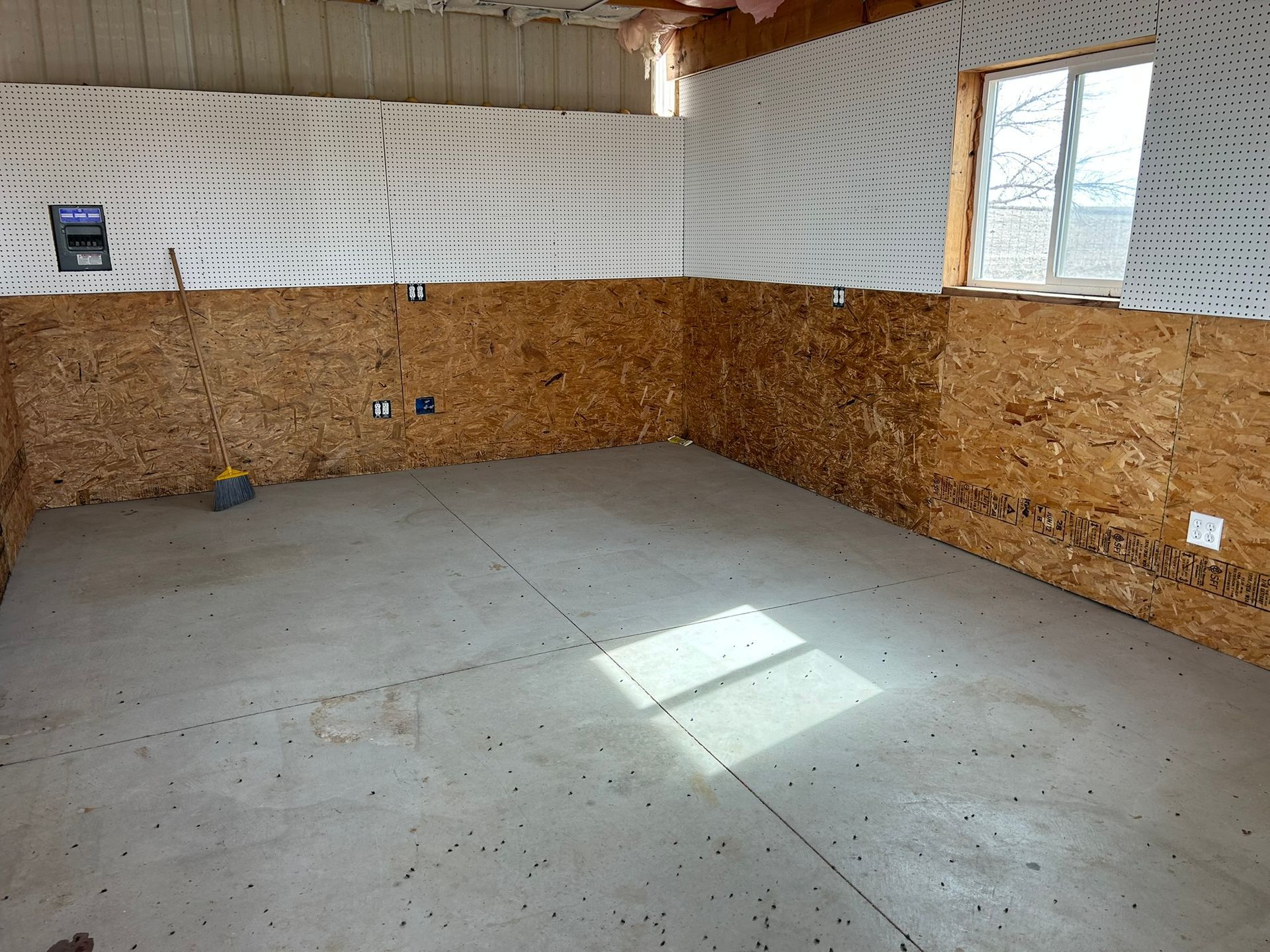 An empty room with a concrete floor and wooden walls