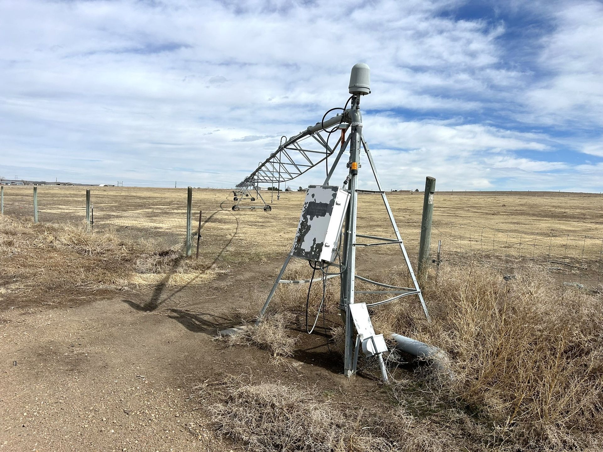 A large metal structure is sitting in the middle of a field.