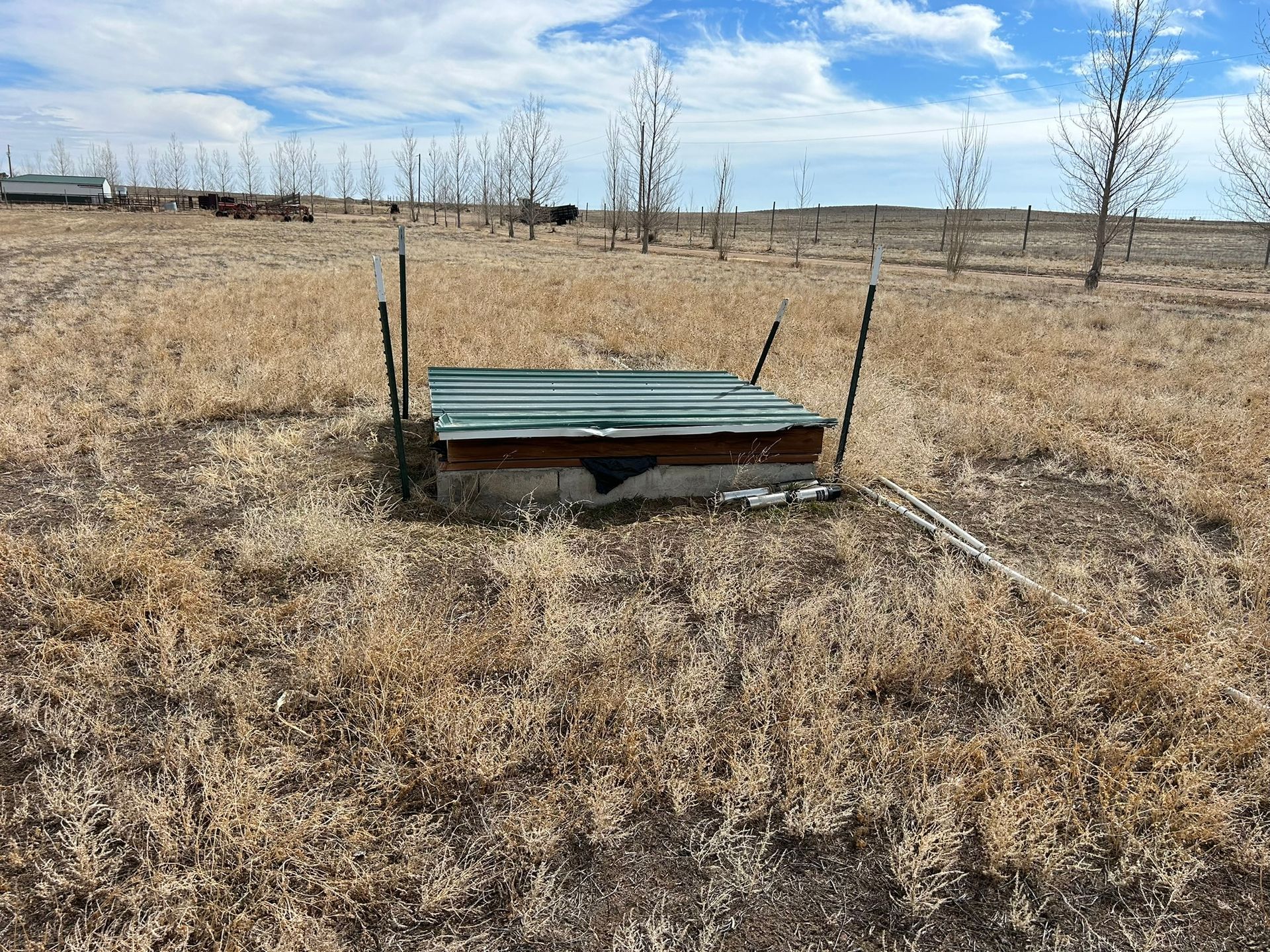 A green roof is sitting in the middle of a dry grass field.