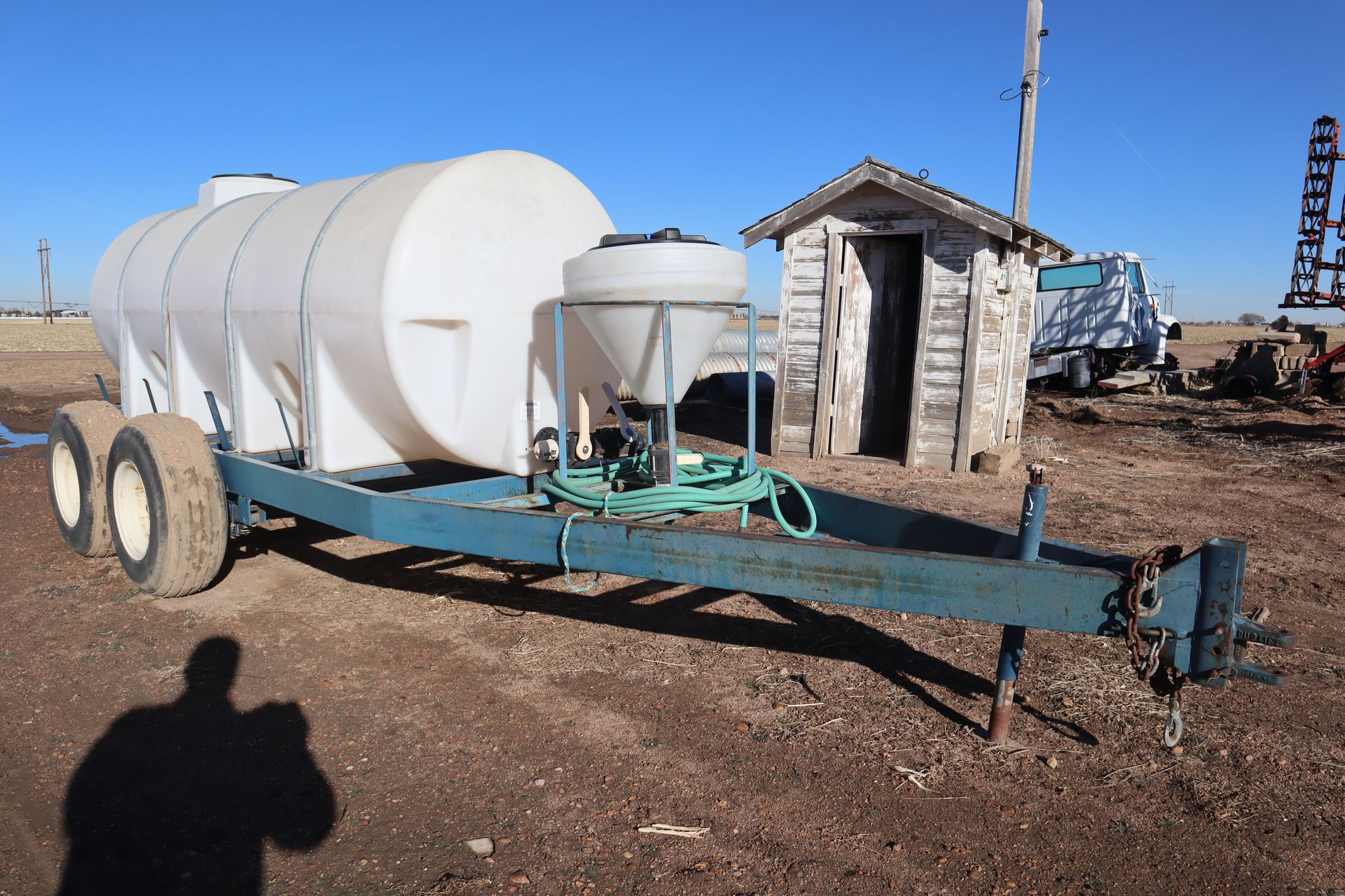 A large white tank is on a trailer in a field.