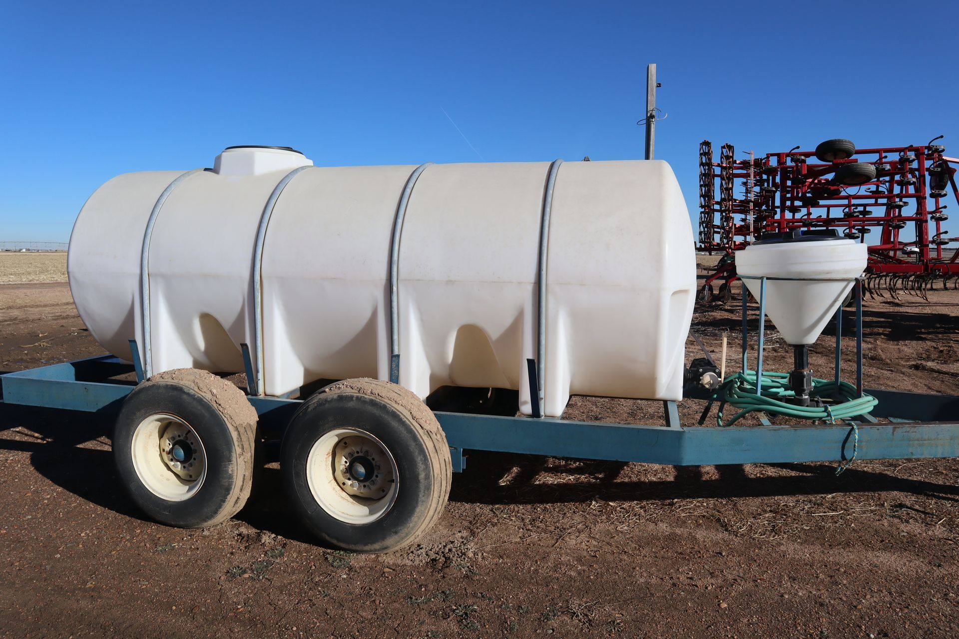 A large white tank is on a trailer in a field.