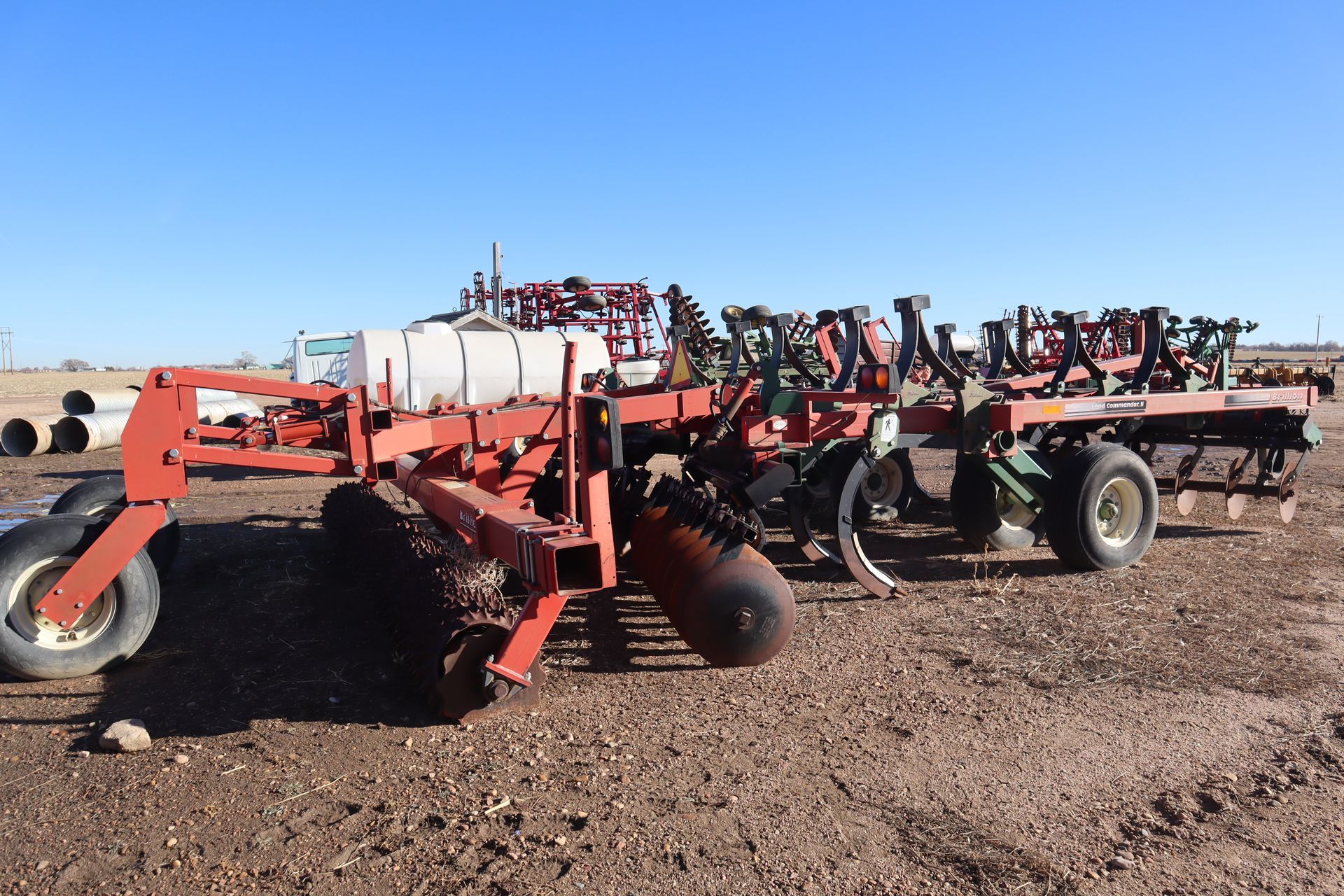 A row of tractors are parked in a dirt field.