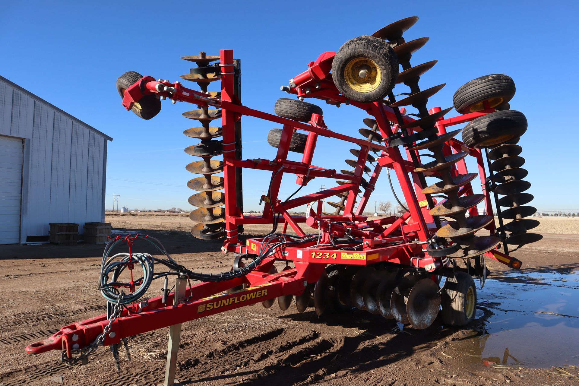 A large red and yellow tractor is parked in a dirt field.
