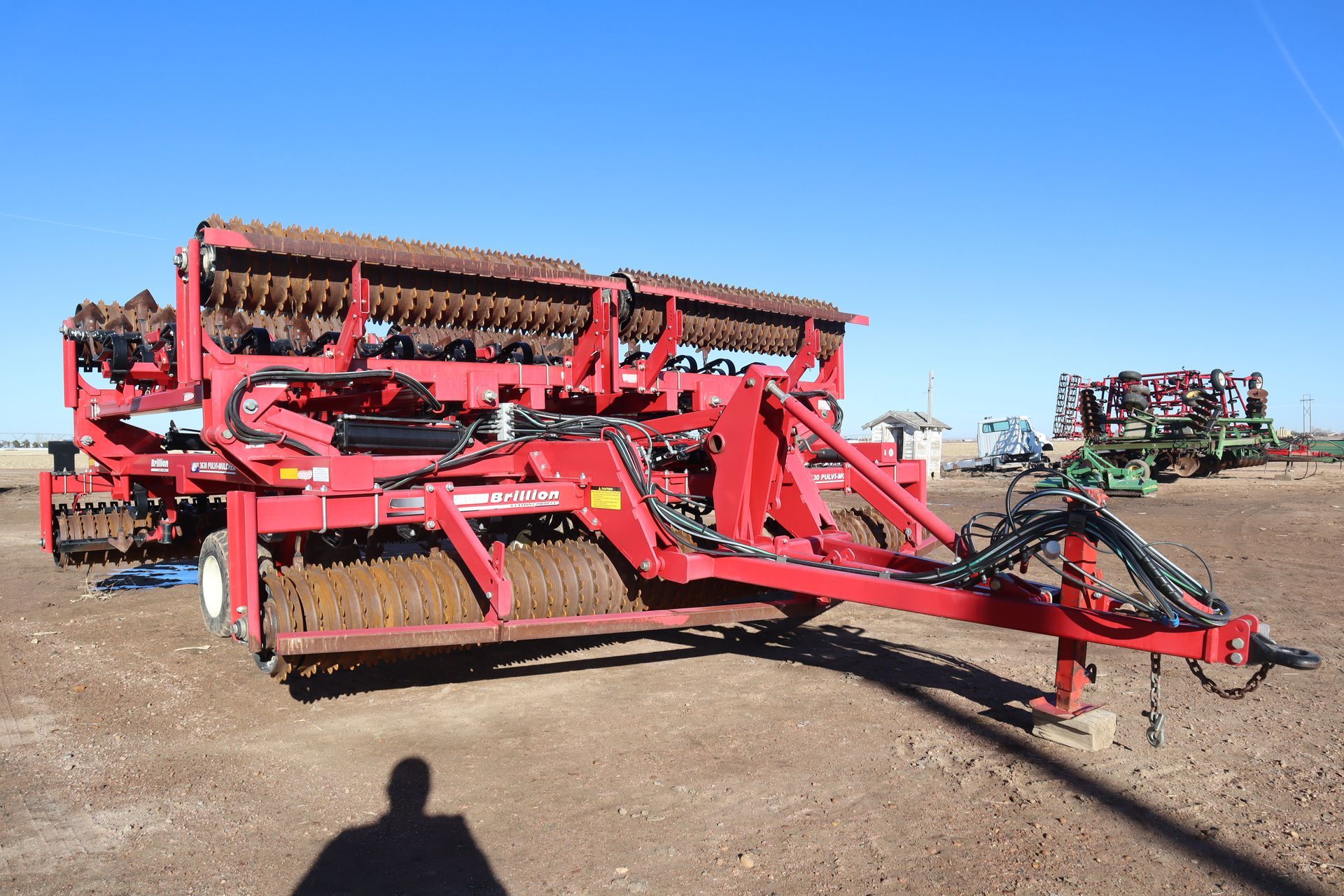 A red tractor is parked in a dirt field