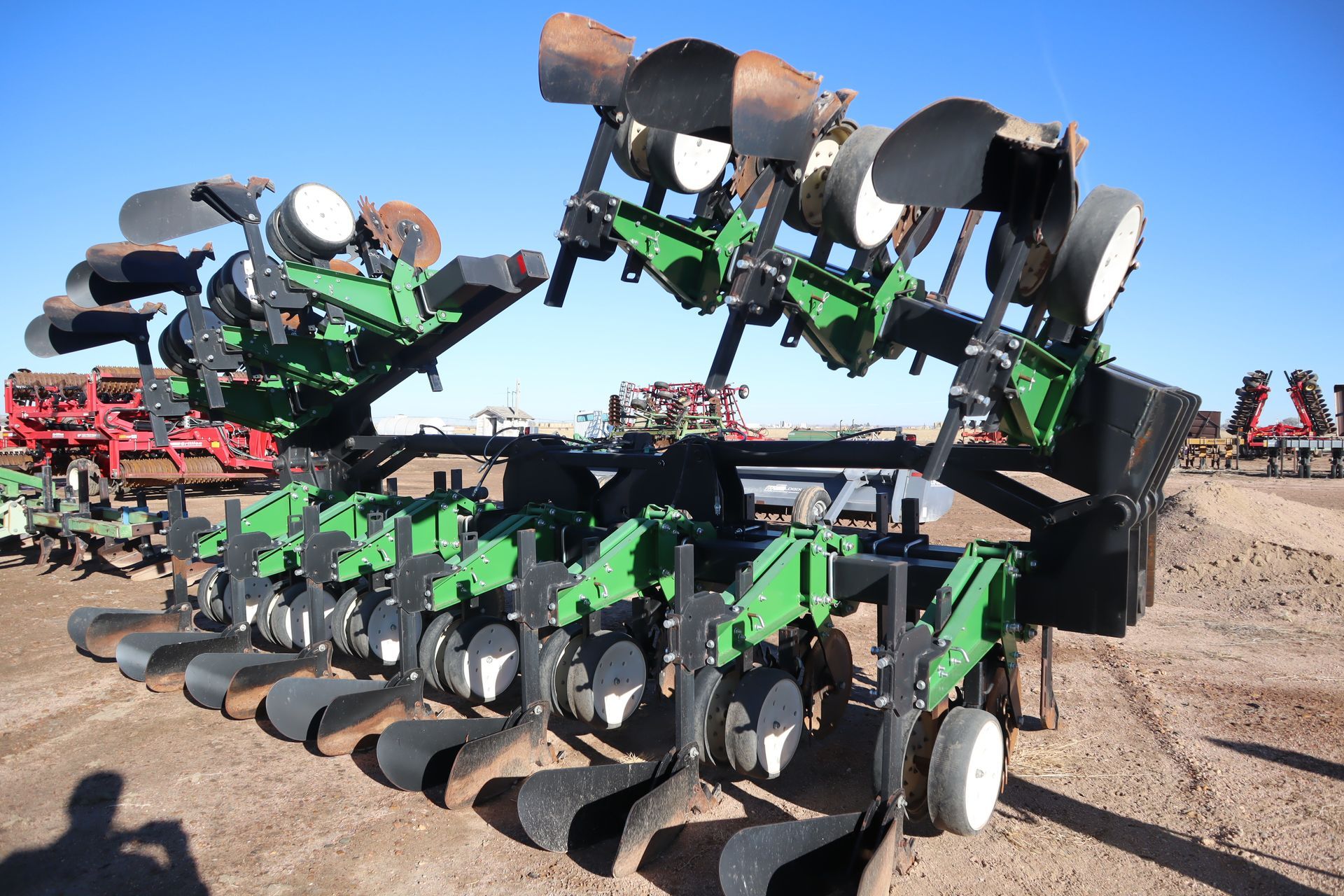A green and black tractor is parked in a dirt field