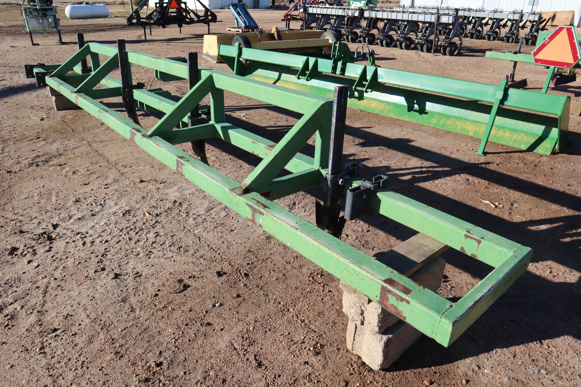 A green metal frame is sitting on a concrete block in the dirt.