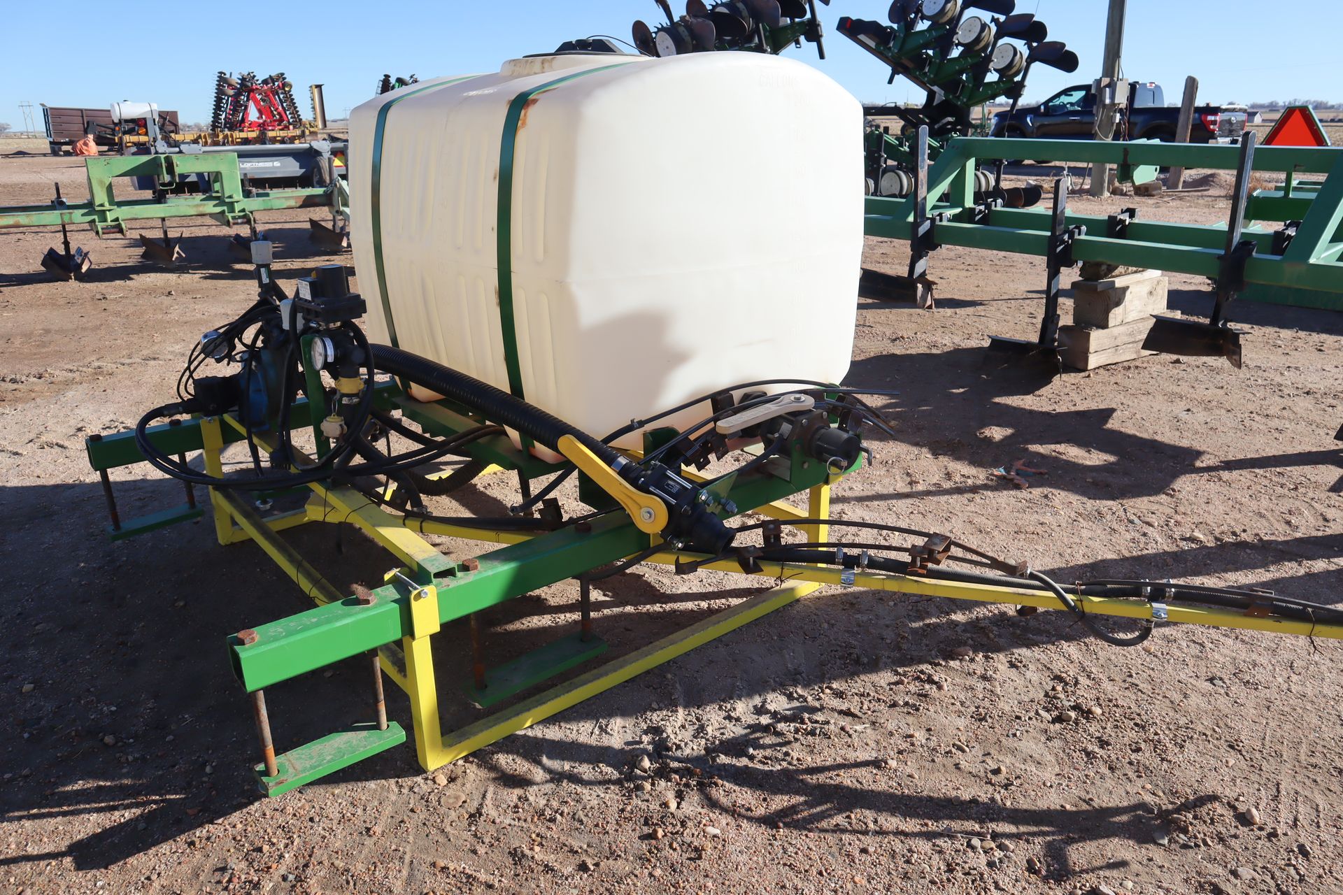 A white tank is attached to a green and yellow trailer